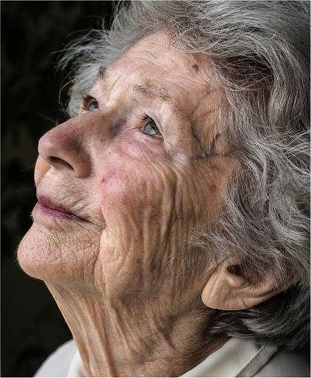 灰髮老婦人帶著平和的表情向上看。 — 高解析度 壁紙