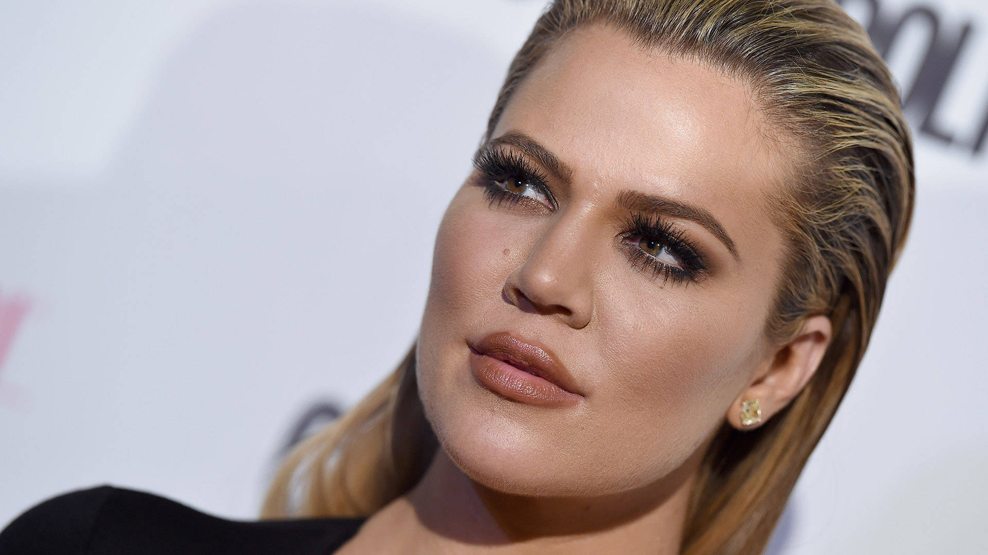 khloe 桌布 壁紙 — Khloé Kardashian 的特寫肖像，金髮和大膽化妝，背景是明亮的白色。