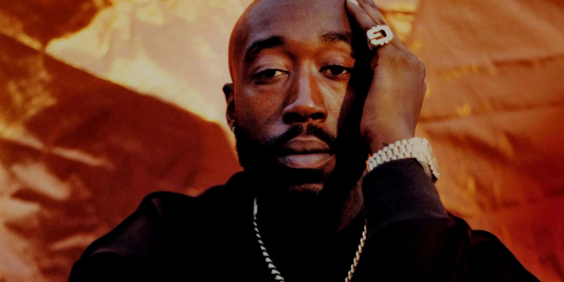  壁紙 — Tupac Shakur 的特寫肖像，手放在額頭上，背景是火橙色紋理。