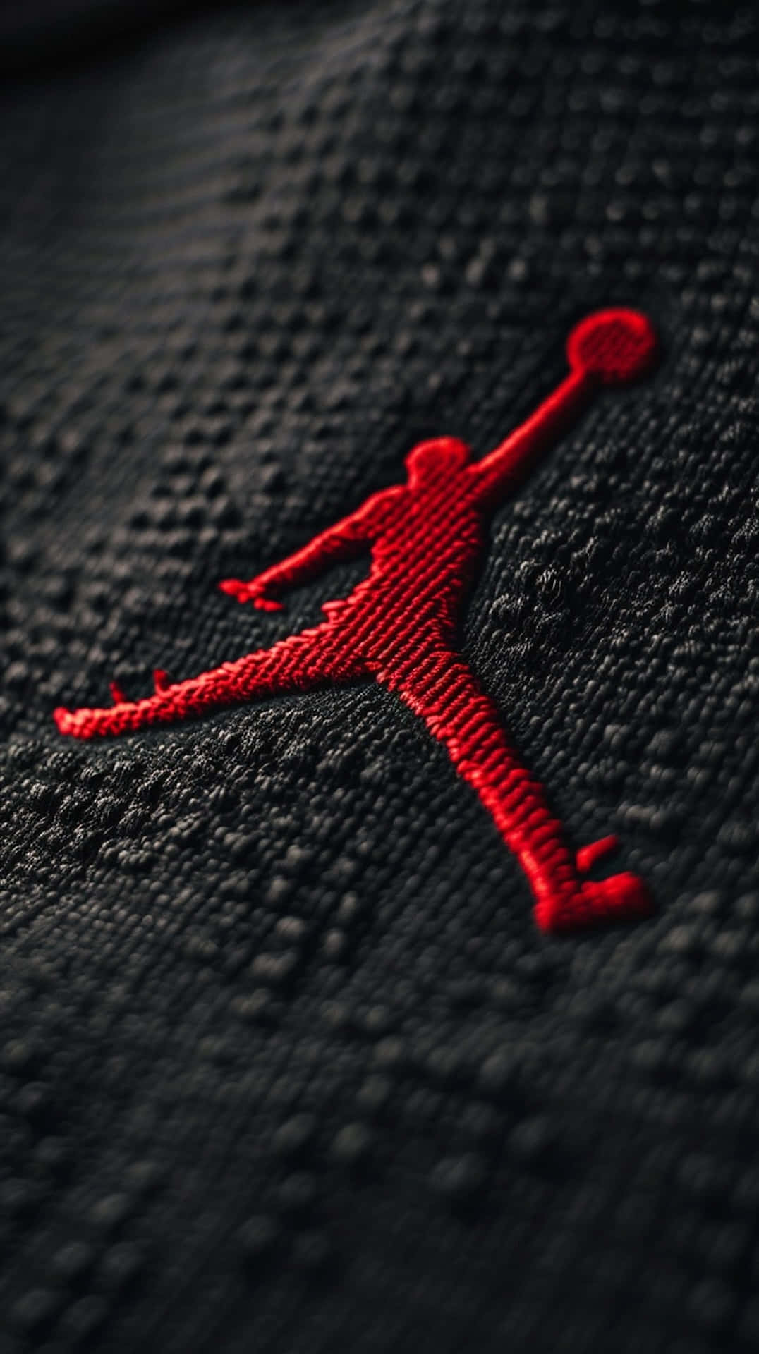  壁紙 — 特寫：在質感黑色布料上繡有鮮紅色Jordan Jumpman標誌。