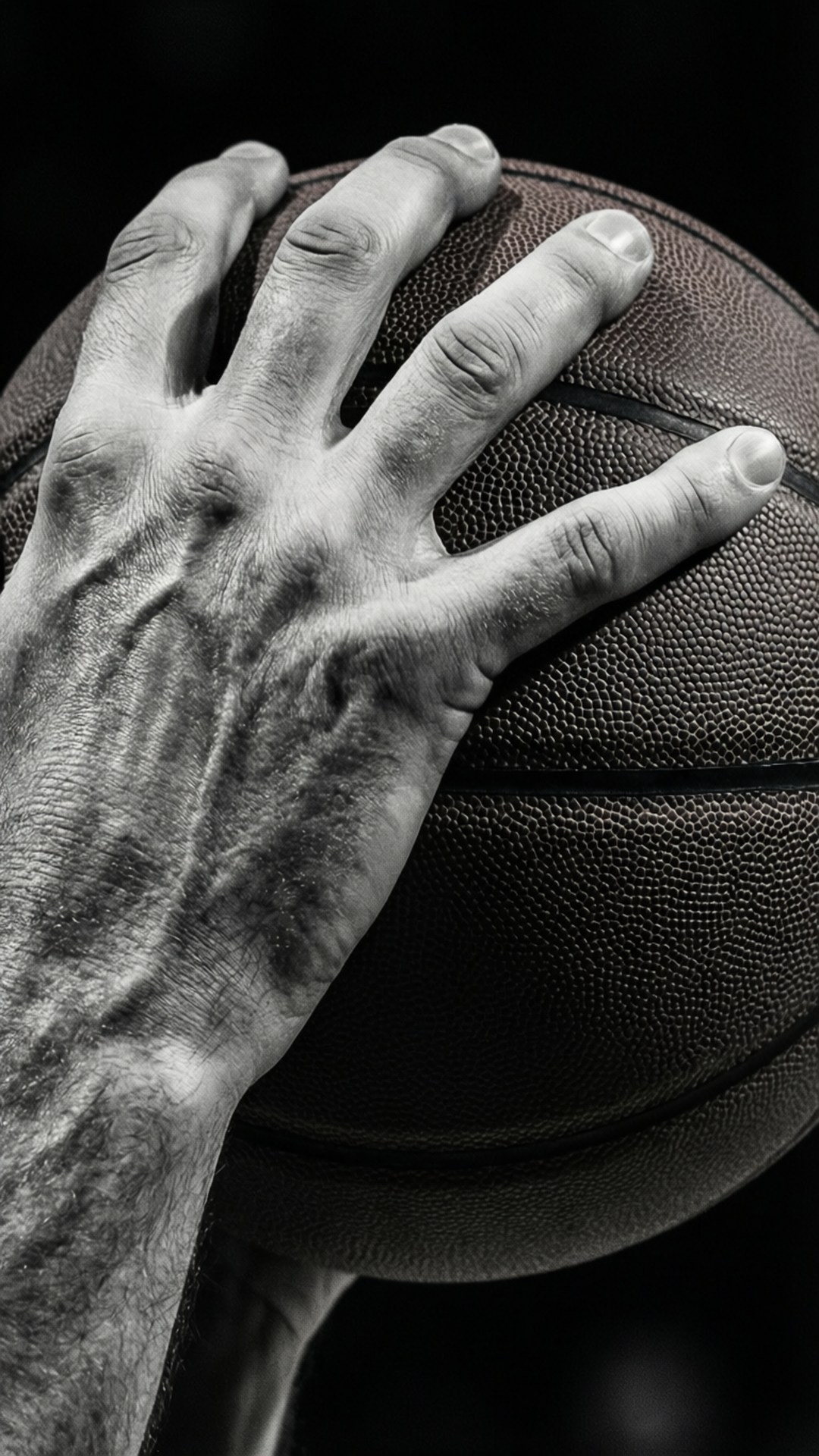 Hands of a Legend 壁紙 — 特寫一隻飽經風霜的手緊握籃球，背景為純黑色。