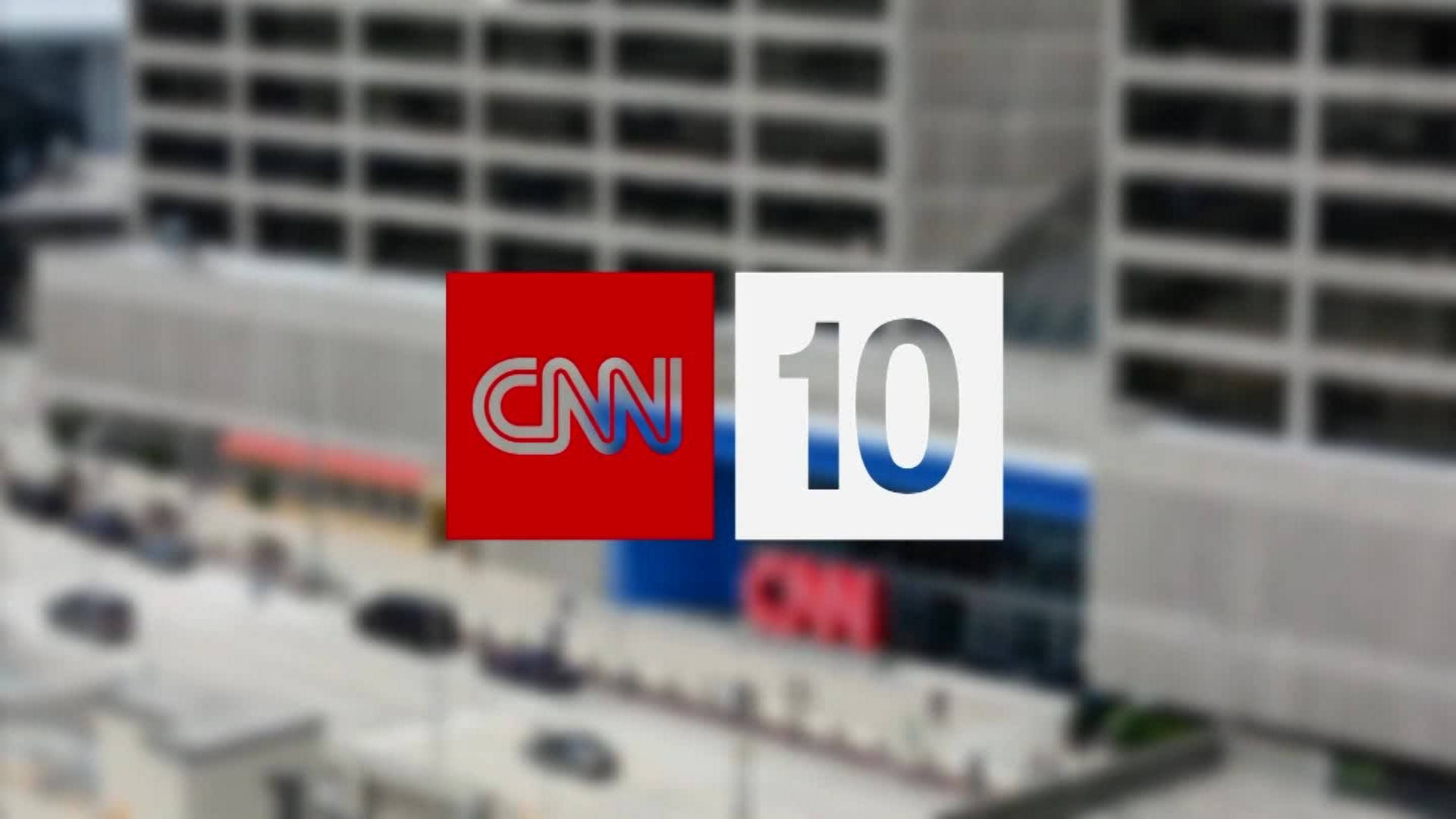 tv 桌布 壁紙 — CNN 10 標誌突出顯示在模糊的城市景觀上，下方有高樓大廈和街道。
