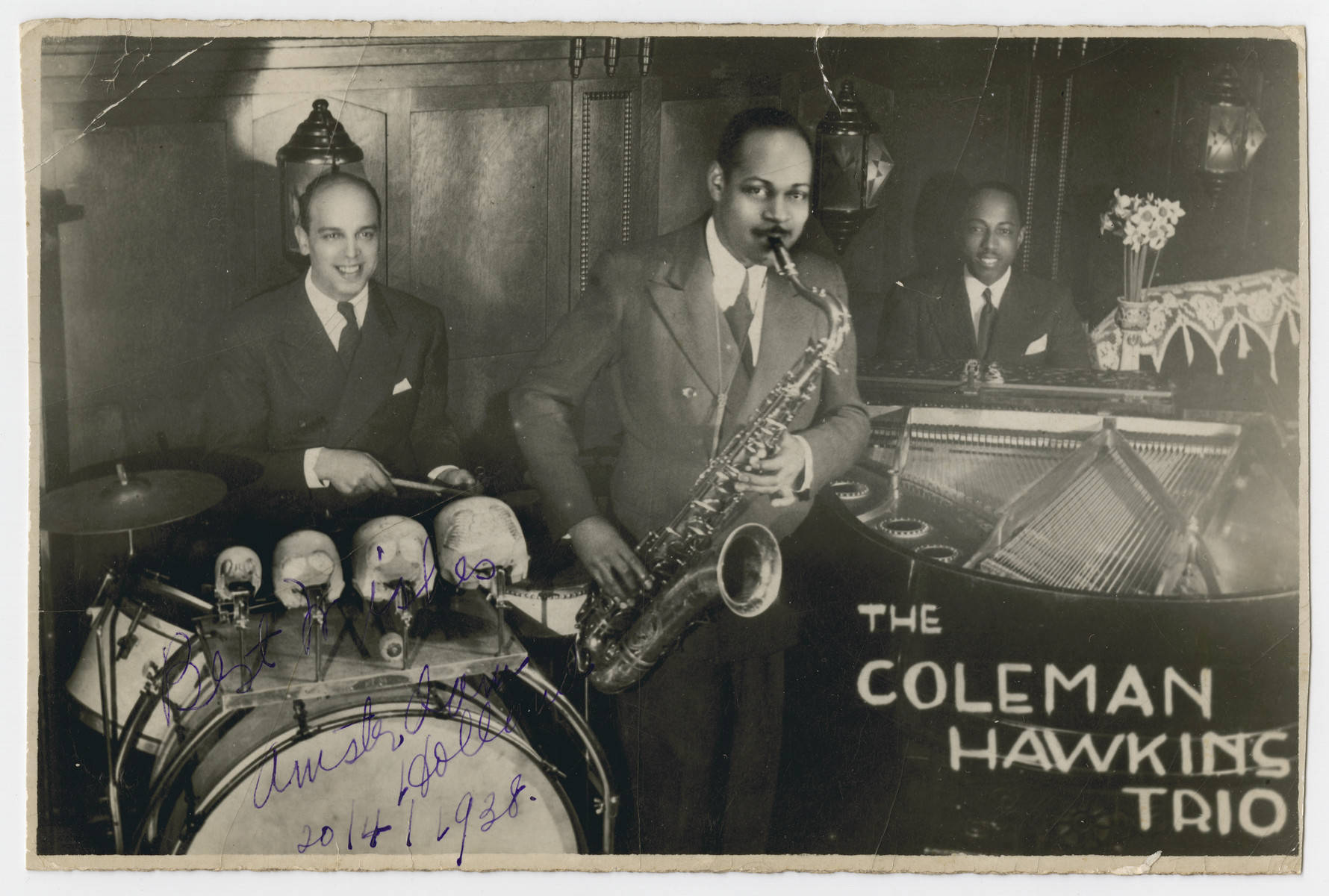 band 桌布 壁紙 — Coleman Hawkins Trio 在燈光昏暗的爵士俱樂部中現場演奏薩克斯風、鼓和鋼琴的復古黑白照片。