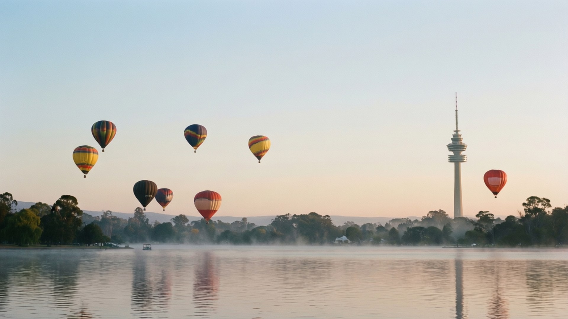 Hot Air Balloons Over Lake 壁紙 — 色彩繽紛的熱氣球漂浮在霧氣瀰漫的湖面上，遠處有一座高塔在黎明時分矗立。