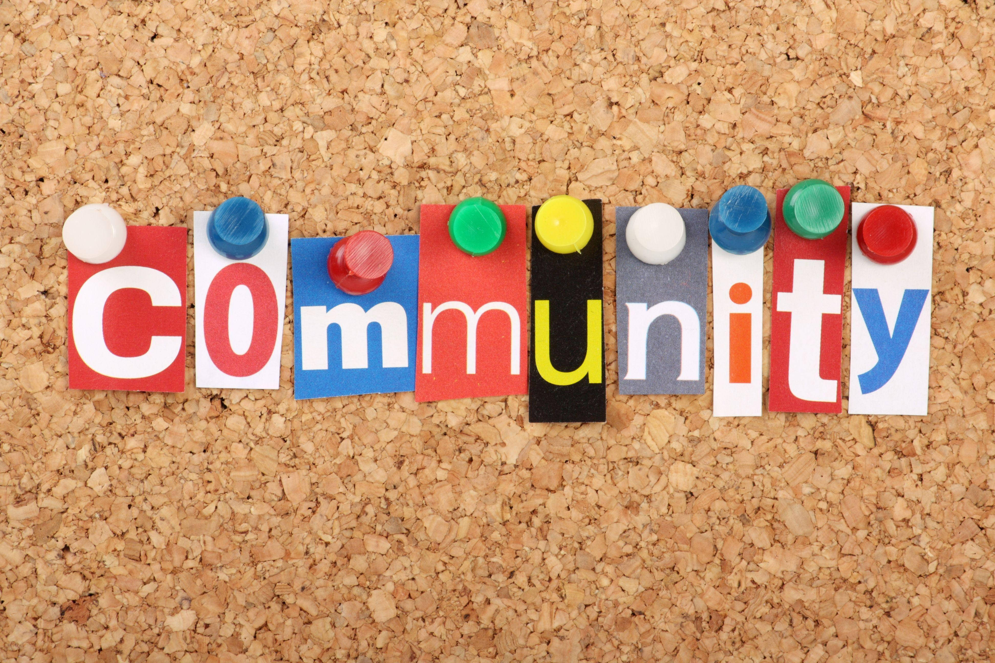 社群 桌布 壁紙 — 「community」這個詞用彩色剪字拼出，並用各種圖釘釘在軟木板上。