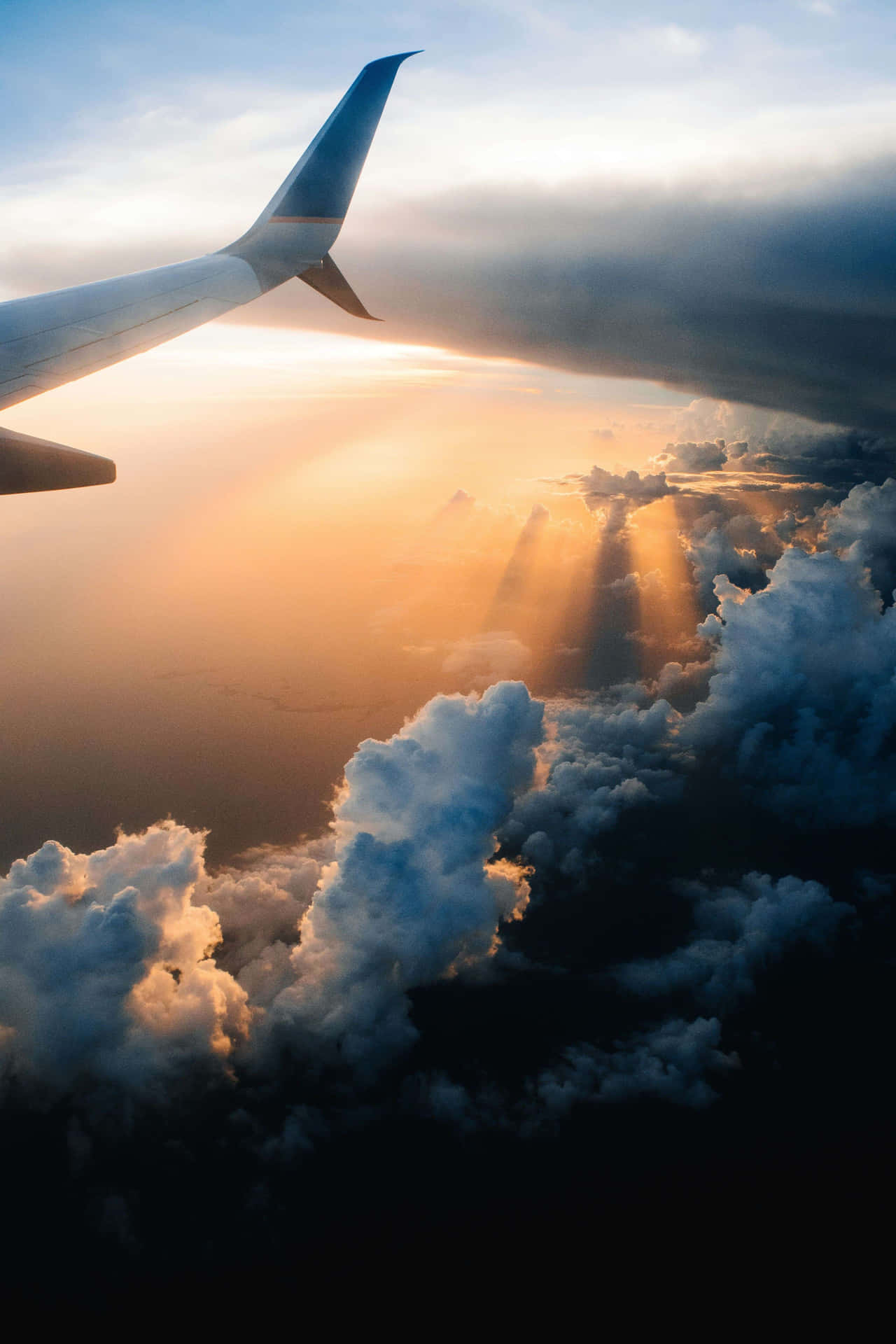  壁紙 — 從飛機窗戶看到的陽光穿過雲層，機翼在畫面中。