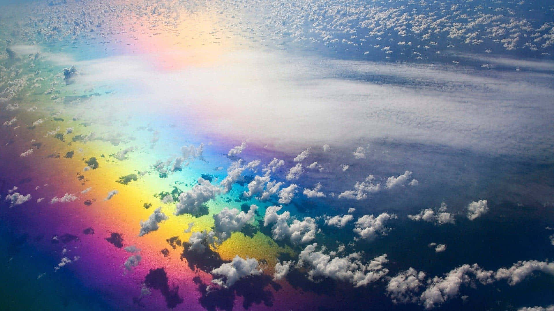  壁紙 — 從高空俯瞰，一道鮮豔的彩虹在深藍色天空中散落的雲層間拱起。