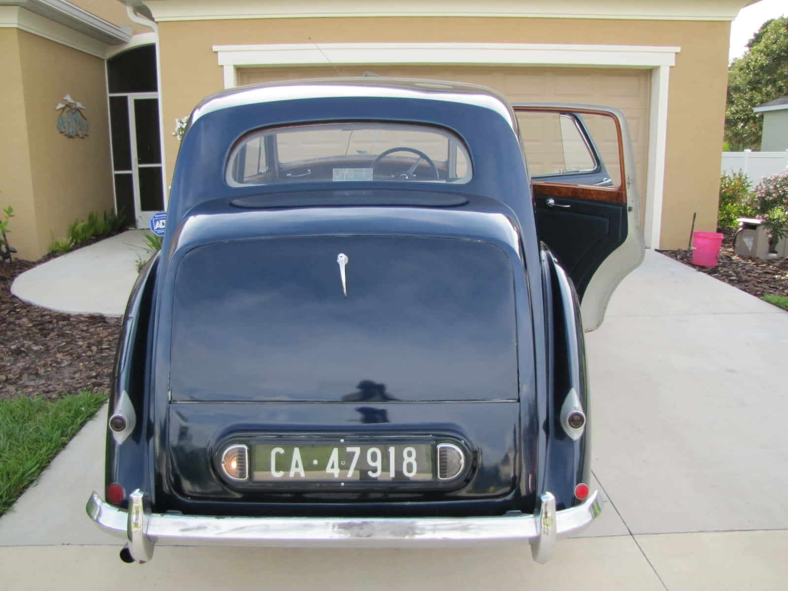 Bentley Mark Vi 桌布 壁紙 — 從後方觀看一輛復古深藍色汽車，車門打開，停泊在住宅車道上。