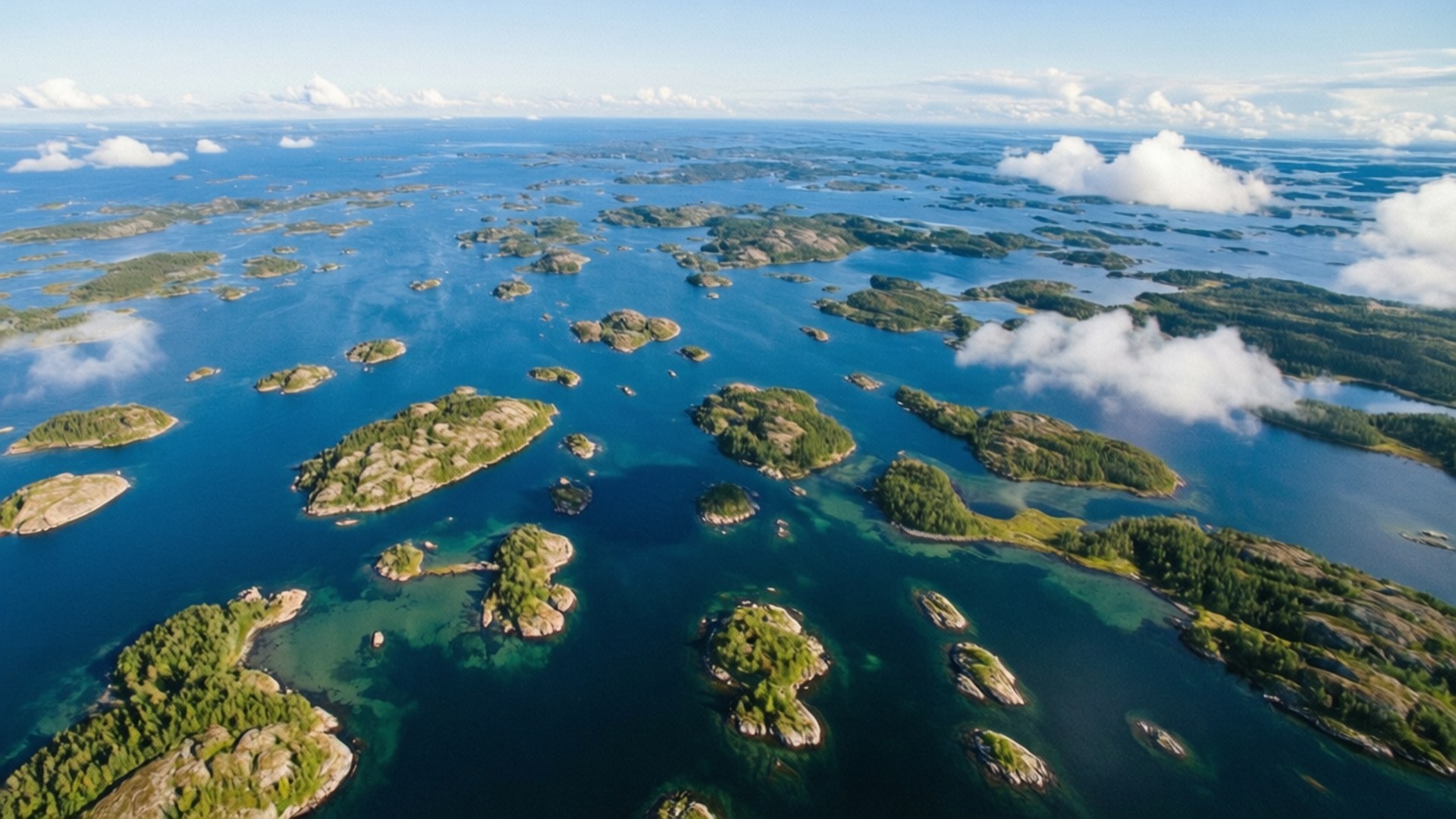 Kvarken Archipelago Summer 壁紙 — 從空中俯瞰，無數森林覆蓋的島嶼散落在深藍色的水域中，天空部分多雲。
