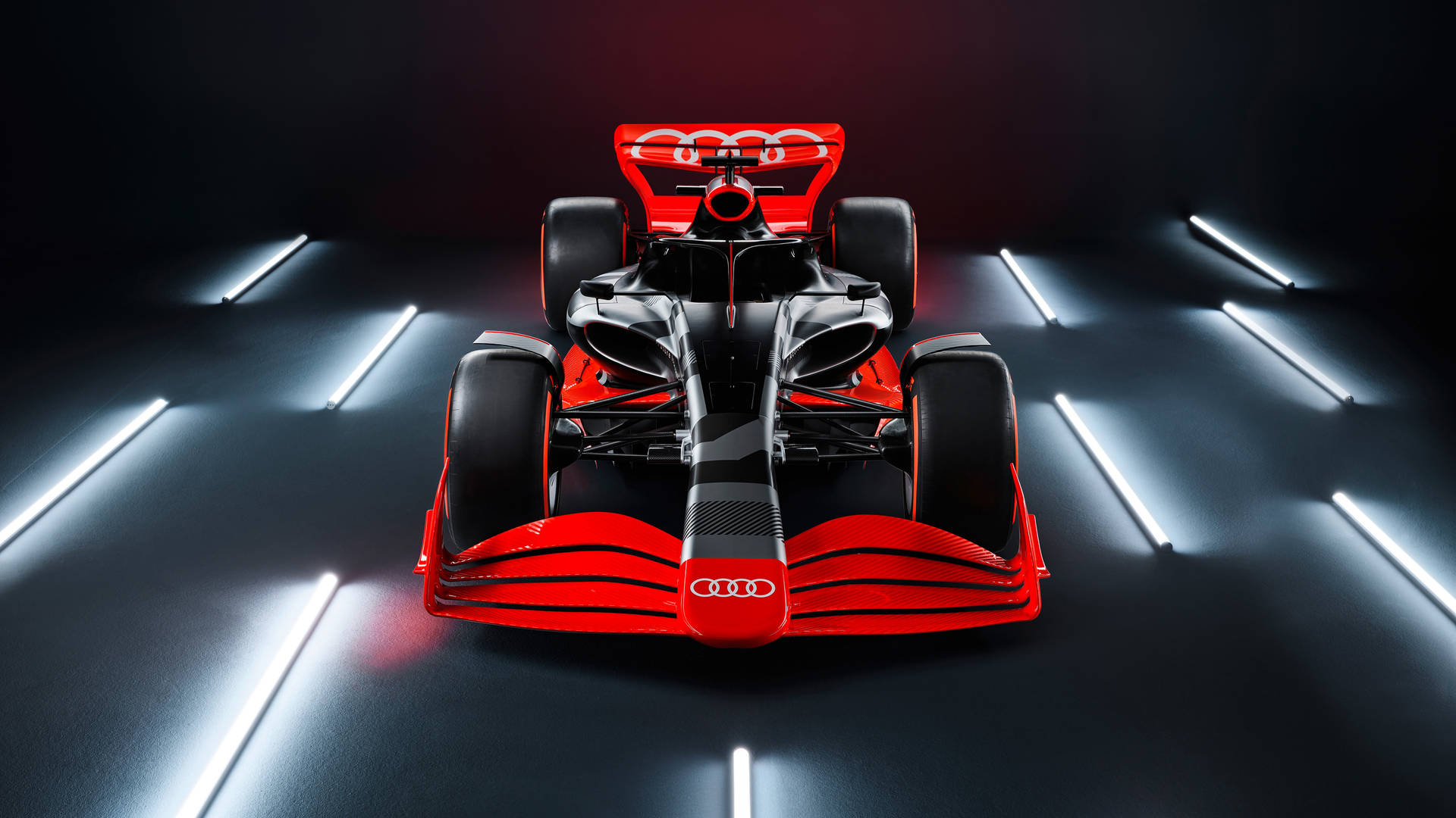 在黑暗工作室中，紅黑相間的奧迪F1賽車被白光照射。 — F1 壁紙