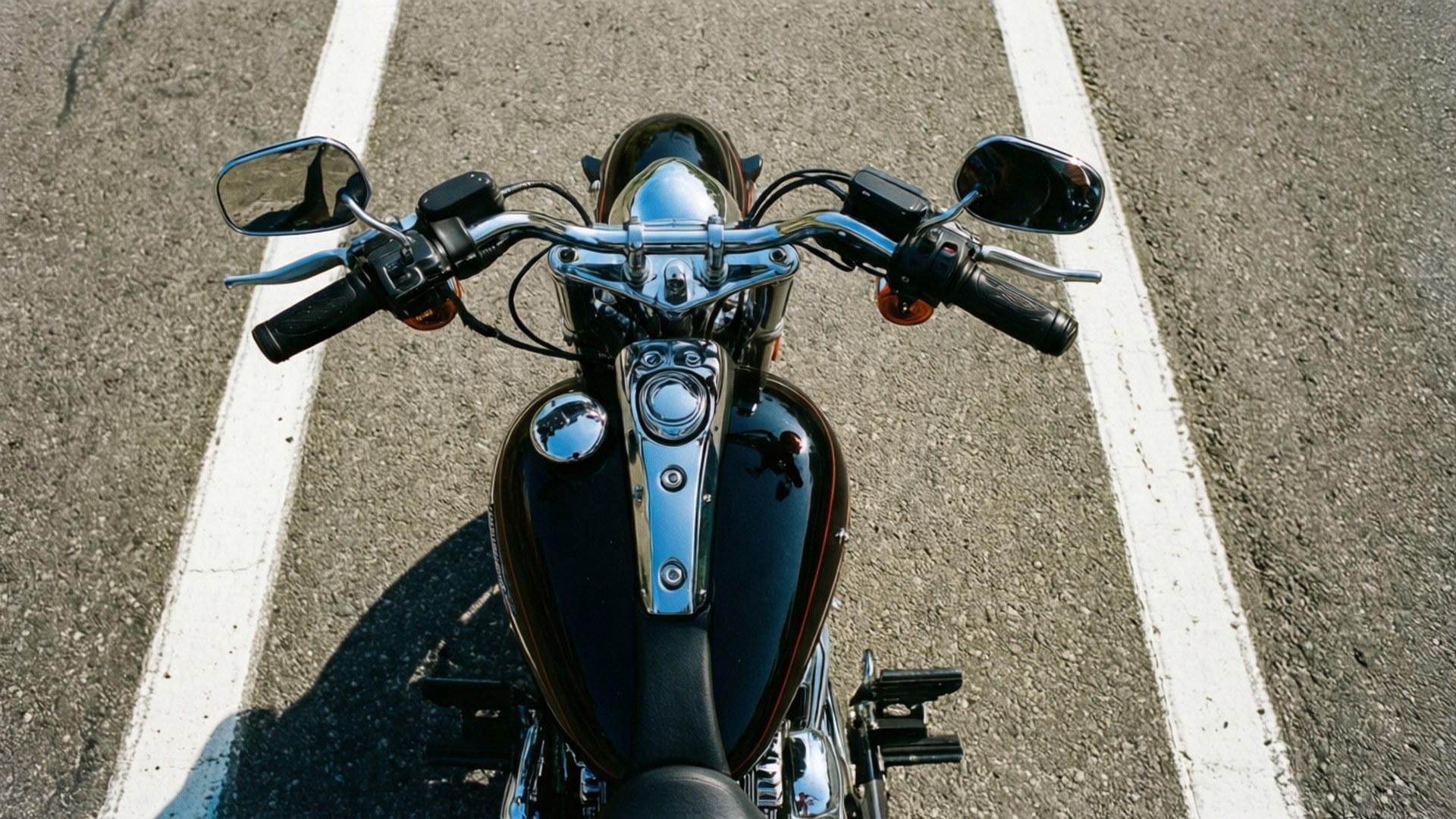 Top Down Dyna 壁紙 — 從上方俯瞰一輛鍍鉻摩托車，黑色油箱，停在柏油路上白色行車線之間。