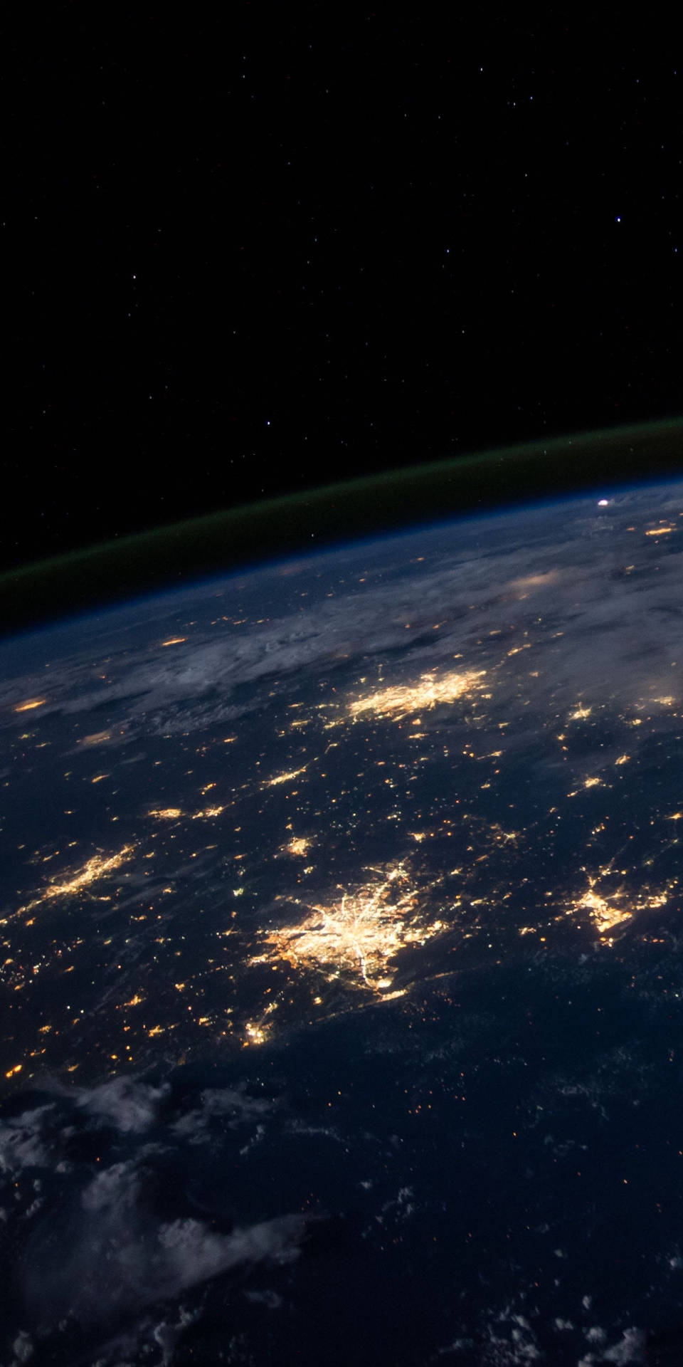 從太空觀看地球的夜景，顯示城市燈光和星空 — Oled 壁紙