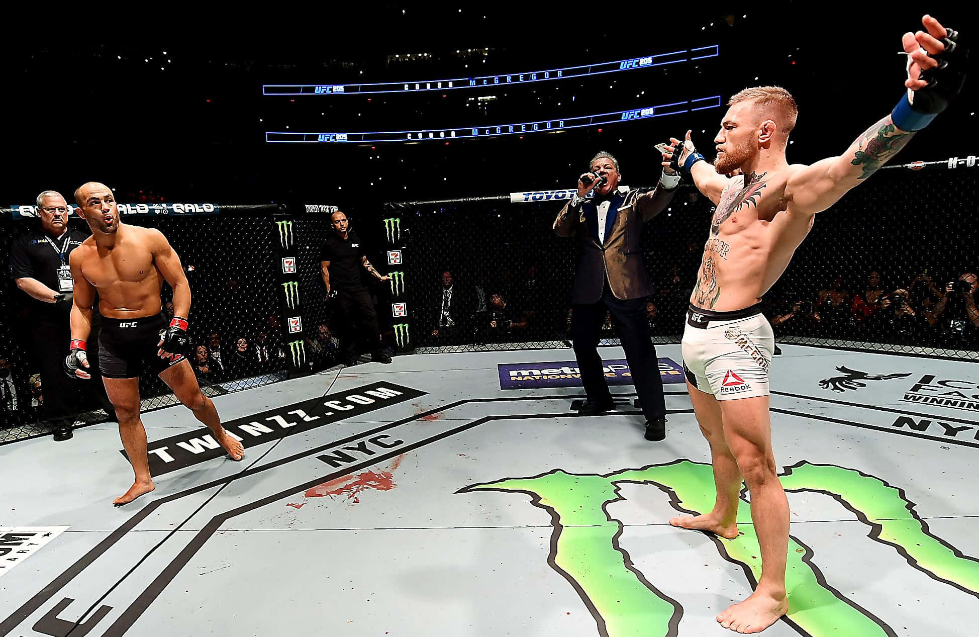 UFC 桌布 壁紙 — Conor McGregor 在UFC八角籠中慶祝勝利，而他的對手在明亮的場館燈光下敗走。