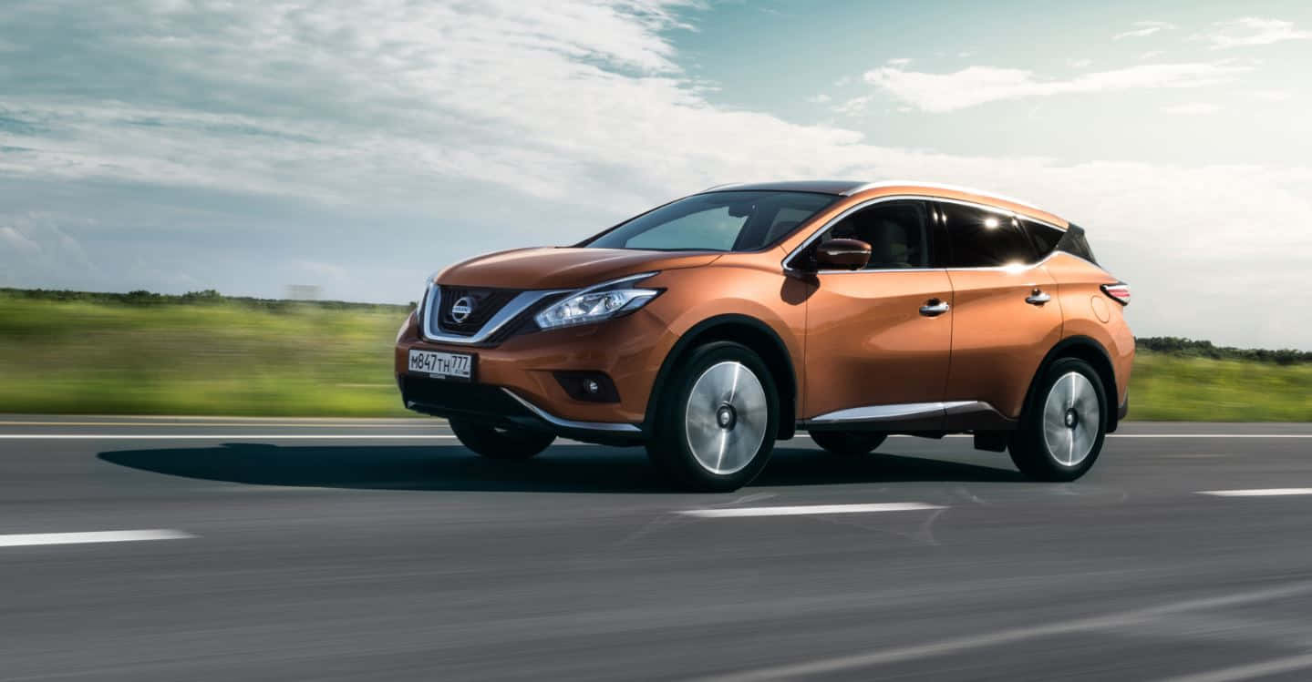 Nissan Murano 桌布 壁紙 — 一輛銅色的日產Murano SUV在部分多雲的天空下，沿著高速公路疾駛，背景是模糊的綠色田野。
