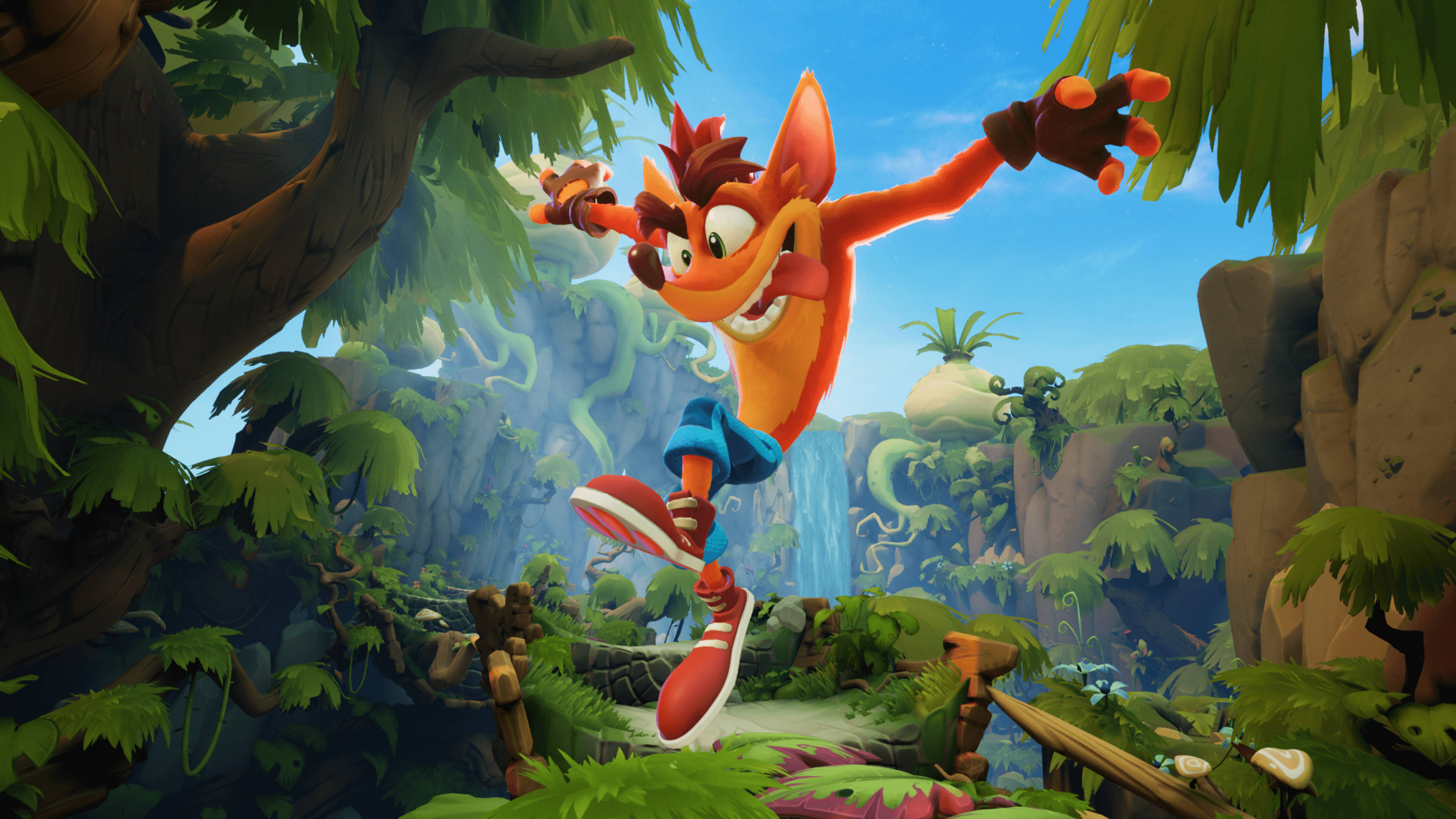 Bandicoot 桌布 壁紙 — Crash Bandicoot 在晴朗的藍天下，快樂地跳過一個充滿瀑布和茂密綠葉的熱帶叢林。