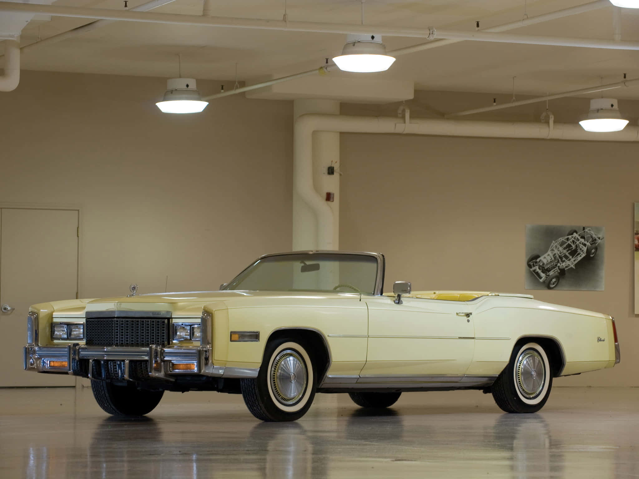 Cadillac Fleetwood 桌布 壁紙 — 一輛奶油色經典凱迪拉克敞篷車在乾淨的室內車庫中，在明亮的頂燈下閃閃發光。