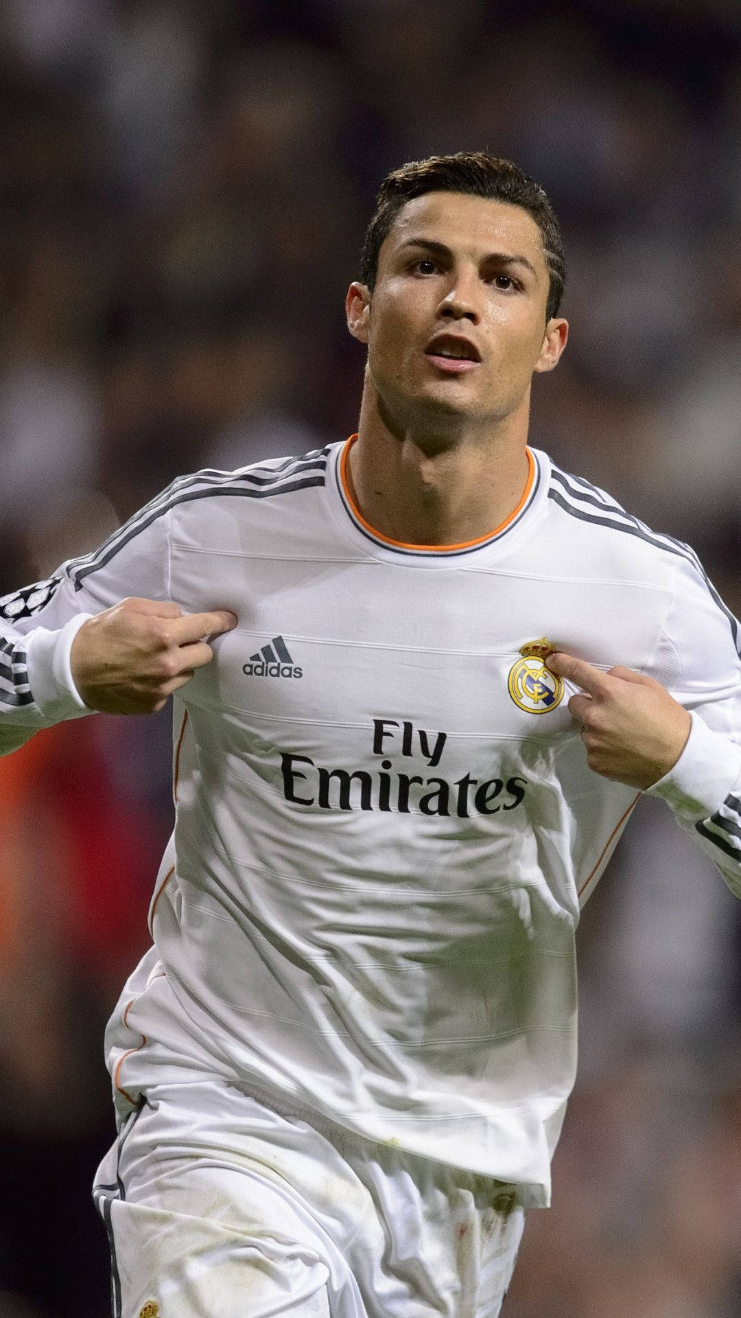 克里斯蒂亞諾·羅納度 桌布 壁紙 — Cristiano Ronaldo 身穿白色皇家馬德里球衣，在夜間足球比賽中專注地指向胸口。
