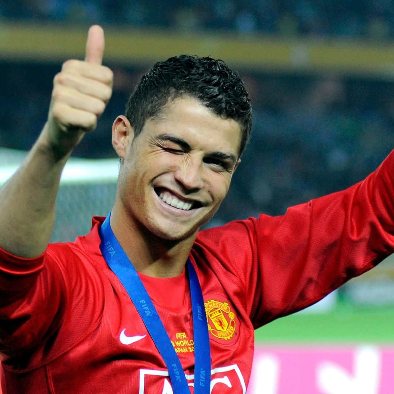 克里斯蒂亞諾·羅納度 桌布 壁紙 — Cristiano Ronaldo 身穿紅色曼聯球衣，佩戴FIFA俱樂部世界盃獎牌，豎起大拇指，滿臉喜悅。