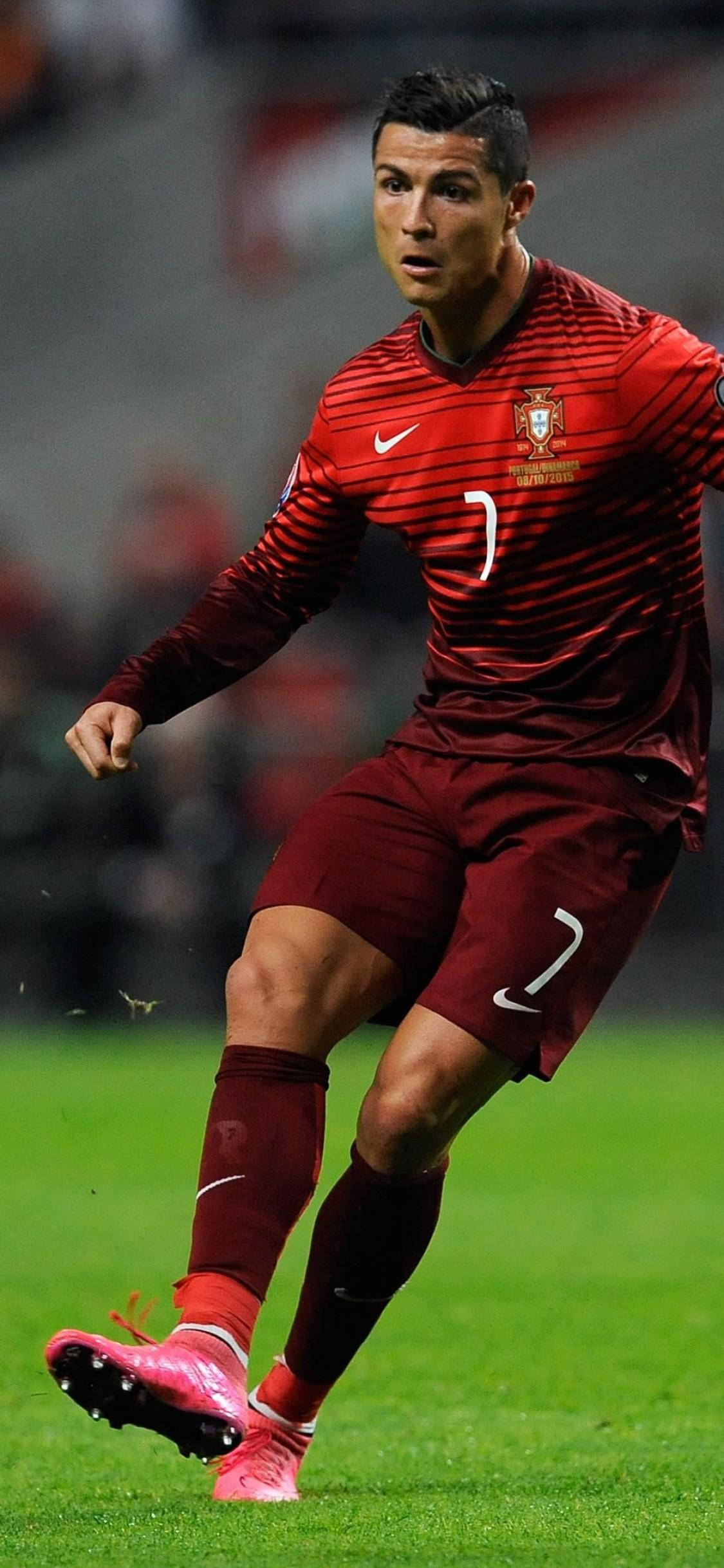 克里斯蒂亞諾·羅納度 桌布 壁紙 — Cristiano Ronaldo 身穿紅色葡萄牙球衣，在球場燈光下於充滿活力的綠色草地上盤球。