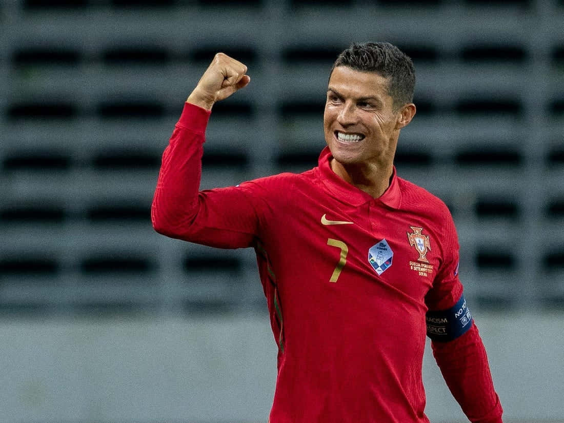 Ronaldo 桌布 壁紙 — Cristiano Ronaldo 身穿紅色葡萄牙球衣，在球場上握拳露出勝利笑容。