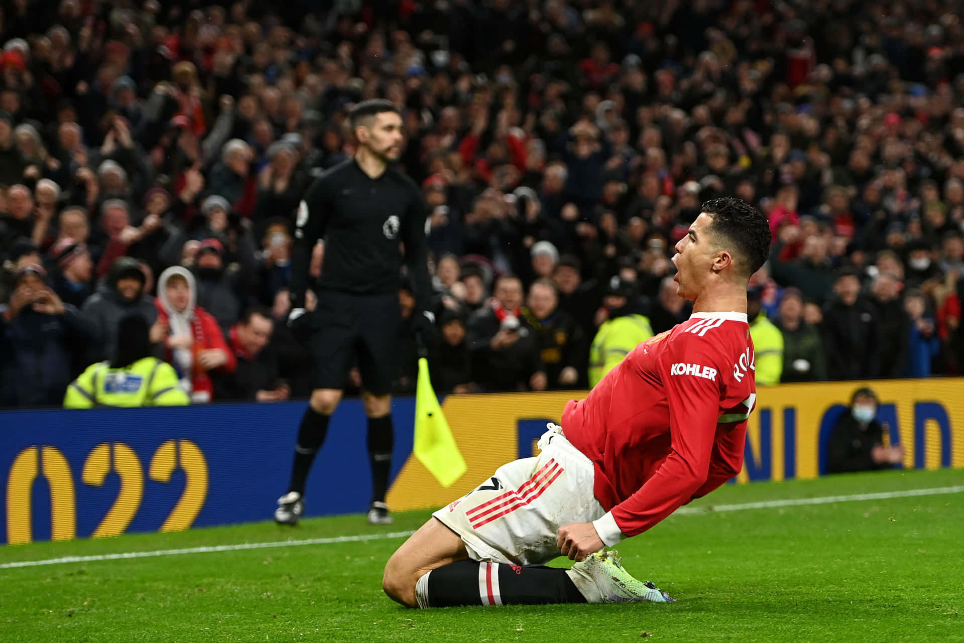  壁紙 — Cristiano Ronaldo 身穿紅色球衣跪在草地上，背景有群眾，慶祝進球。