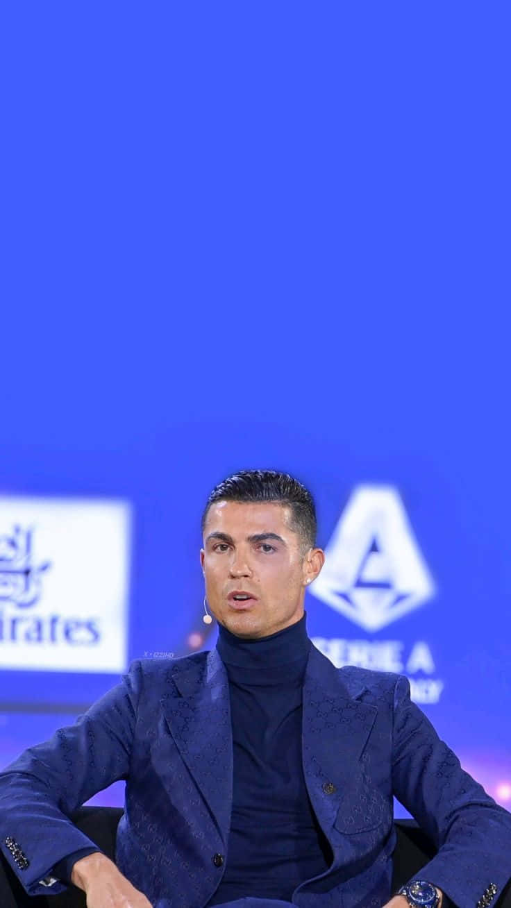  壁紙 — Cristiano Ronaldo 在記者會上發言，身穿深藍色西裝，背景是鮮明的藍色品牌背景。