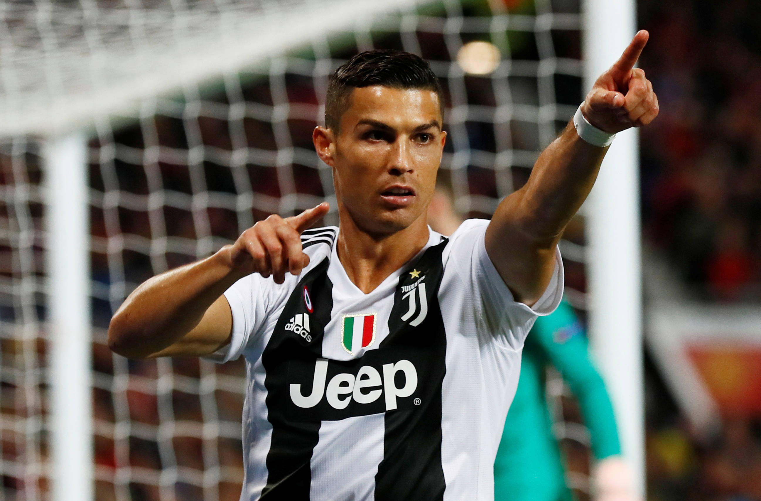 Ronaldo 桌布 壁紙 — Cristiano Ronaldo 身穿尤文圖斯球衣，在模糊的球場背景下雙臂向上指慶祝進球。