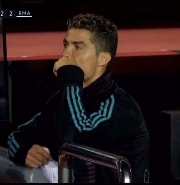 eldon 壁紙 — Cristiano Ronaldo 沉思地坐在體育場座位上，身穿帶有青綠色條紋的黑色天鵝絨運動服，手掩著嘴。