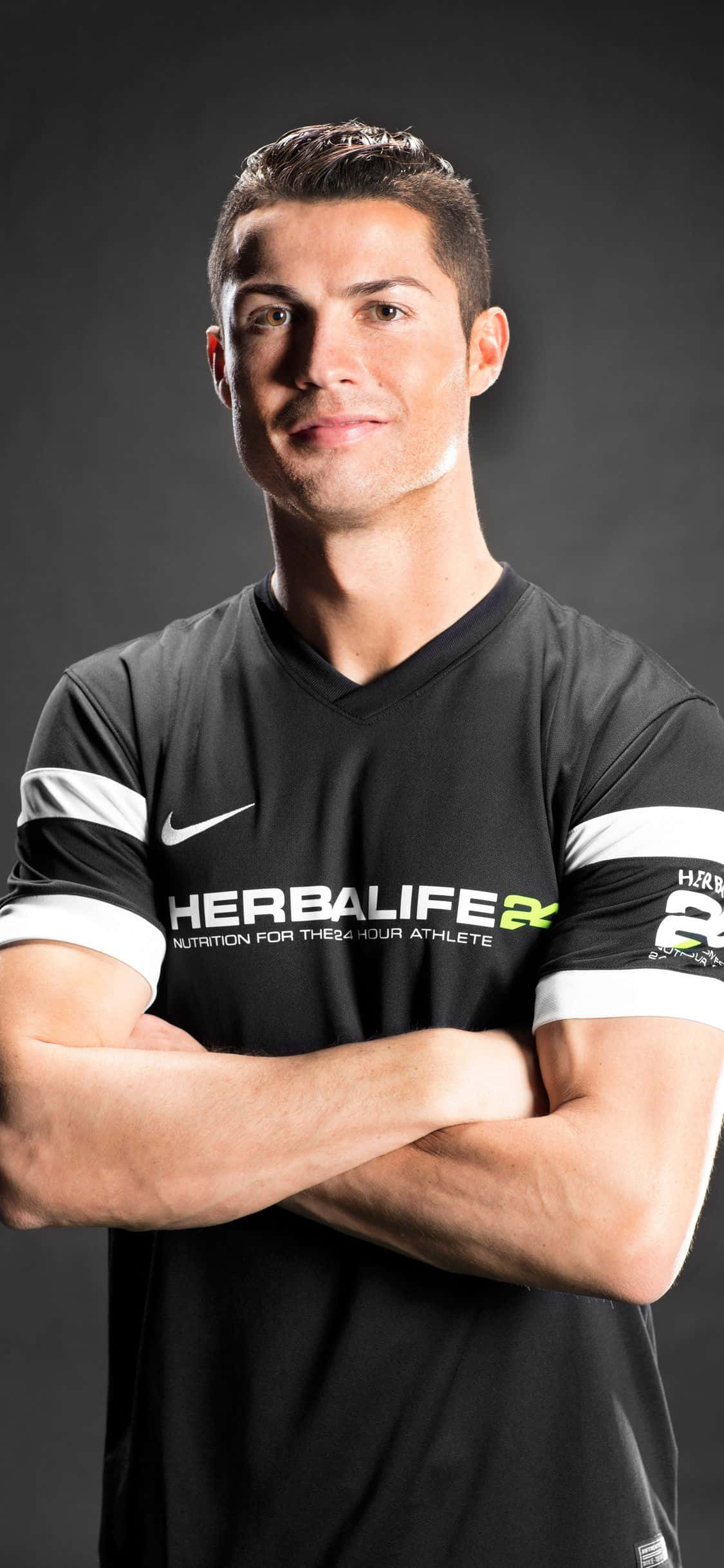 Ronaldo 桌布 壁紙 — Cristiano Ronaldo 自信地交叉雙臂站立，身穿黑色Herbalife Nutrition球衣，背景為深色攝影棚。