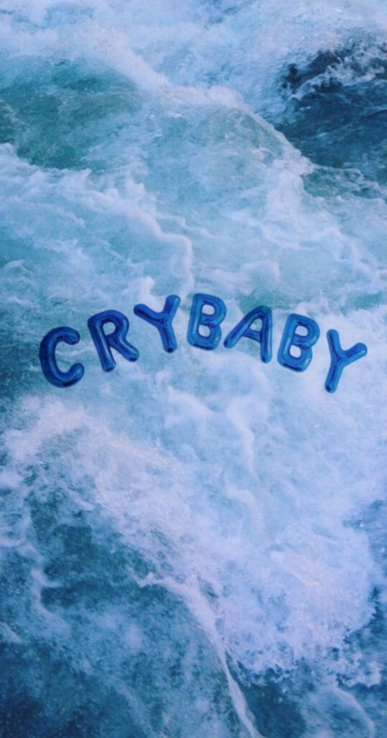 簡約藍色美學 桌布 壁紙 — 「crybaby」這個詞漂浮在洶湧的藍色海浪中，帶有泡沫狀的白色浪花。