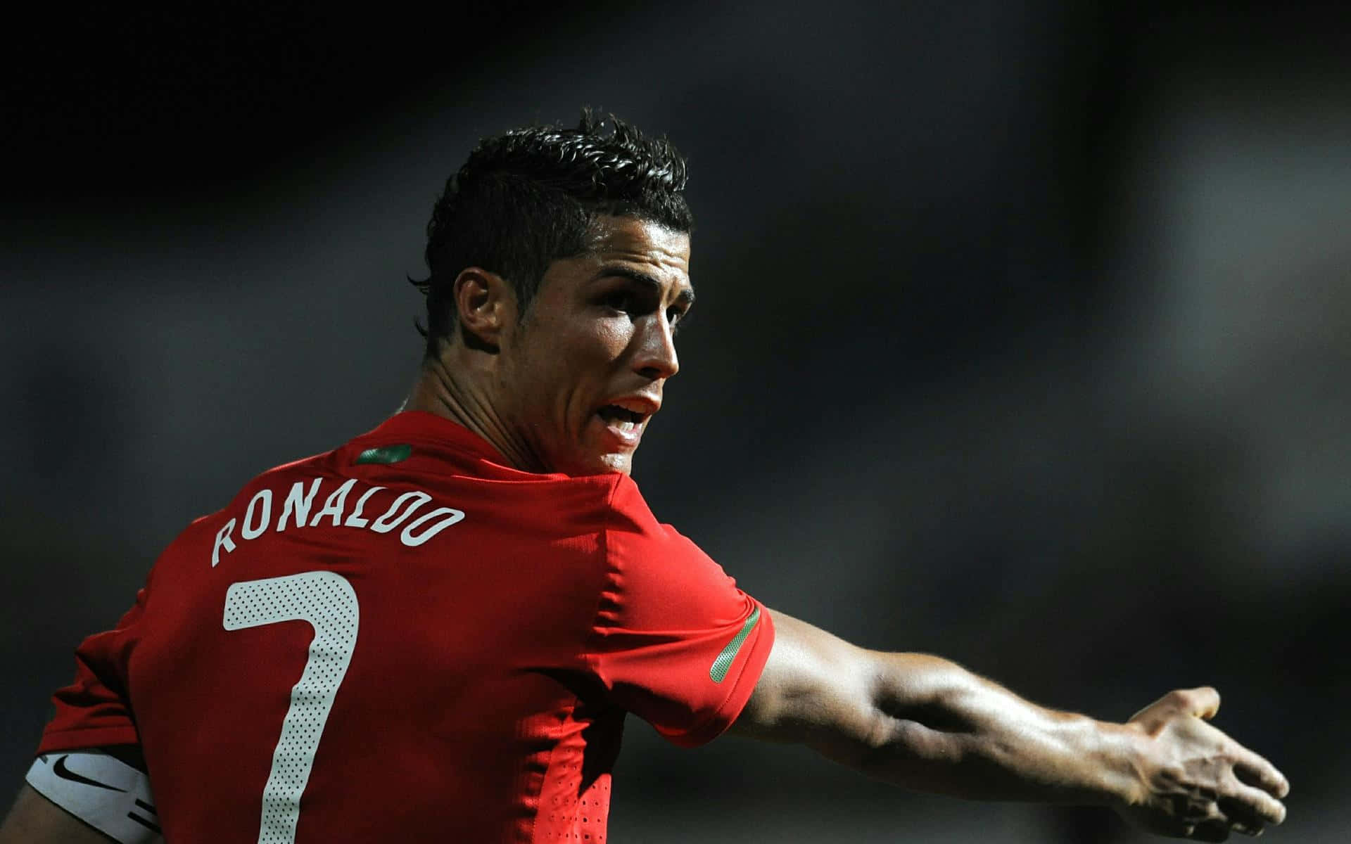 Ronaldo 桌布 壁紙 — C羅身穿紅色葡萄牙7號球衣，在球場燈光下張開手臂慶祝。