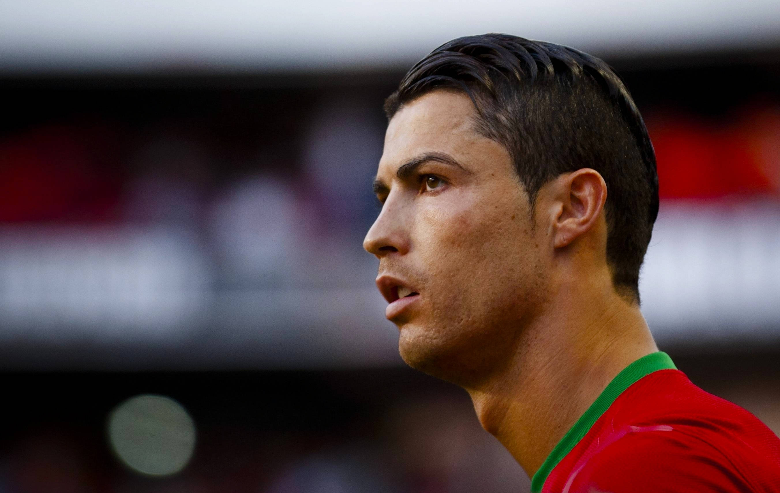 Cr7 桌布 壁紙 — C羅身穿紅色葡萄牙球衣，在比賽中專注的近距離側面照。