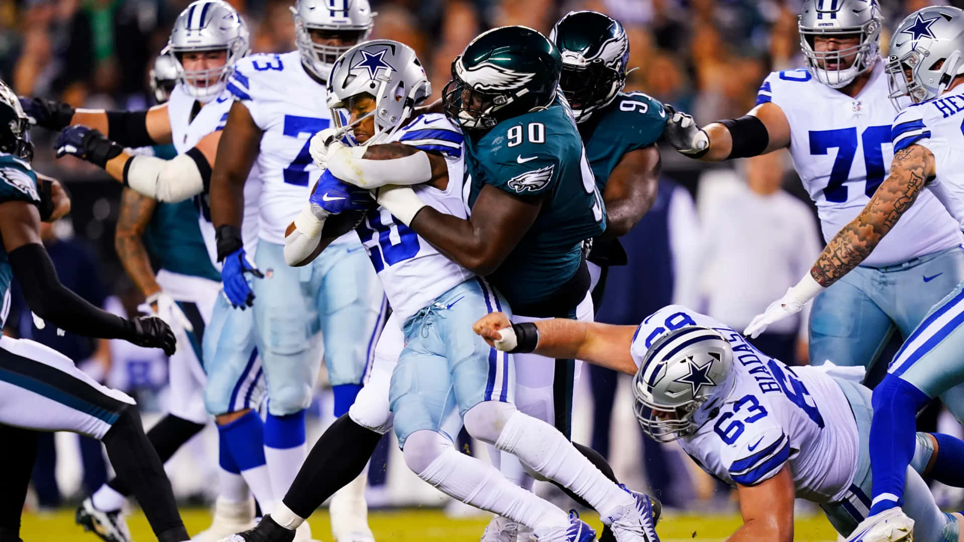  壁紙 — 達拉斯牛仔隊的跑衛在充滿活力的NFL比賽中被費城老鷹隊的防守球員擒抱。
