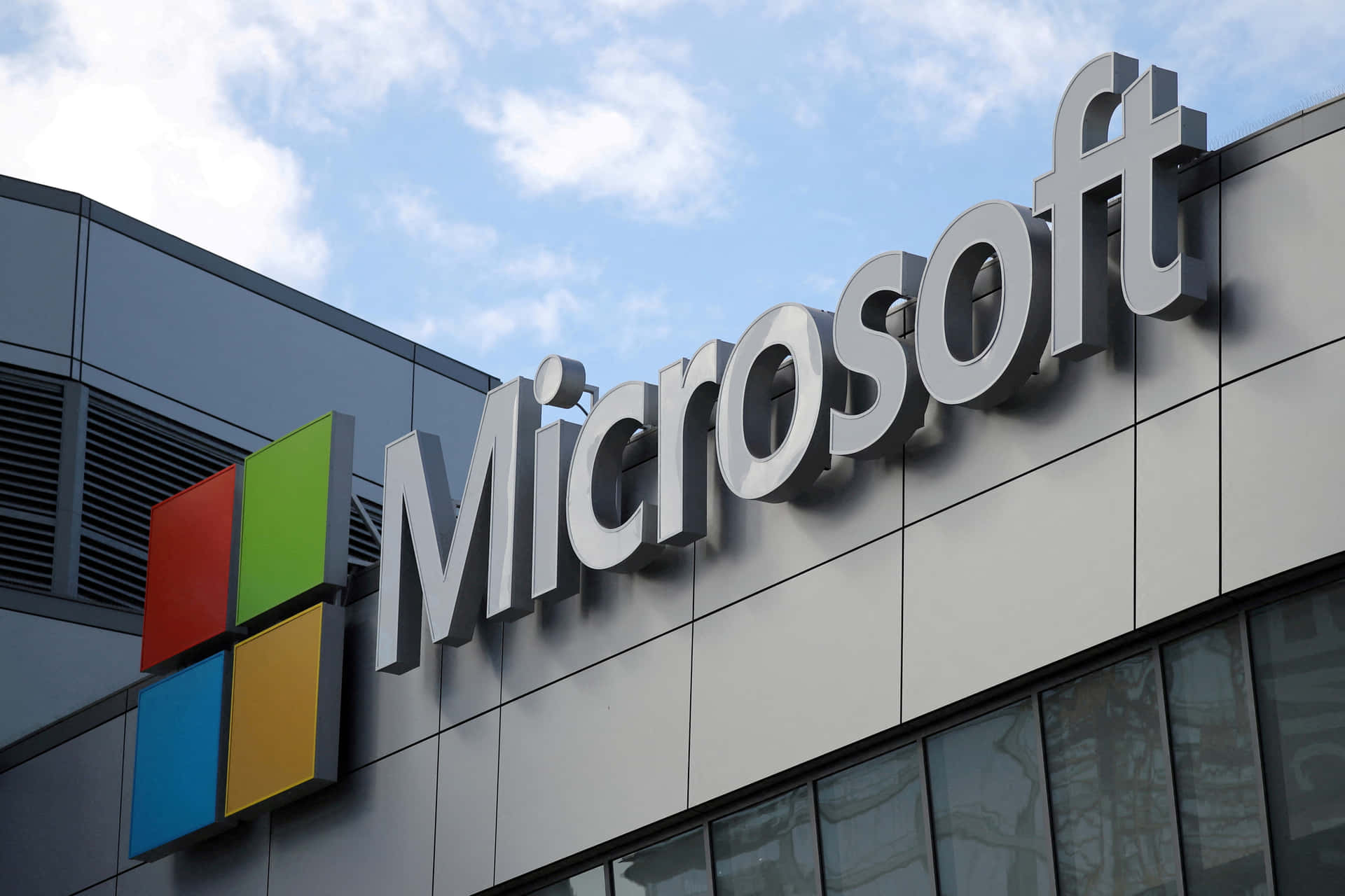 Microsoft企業標誌在現代辦公樓外牆上。 — Microsoft Teams 壁紙