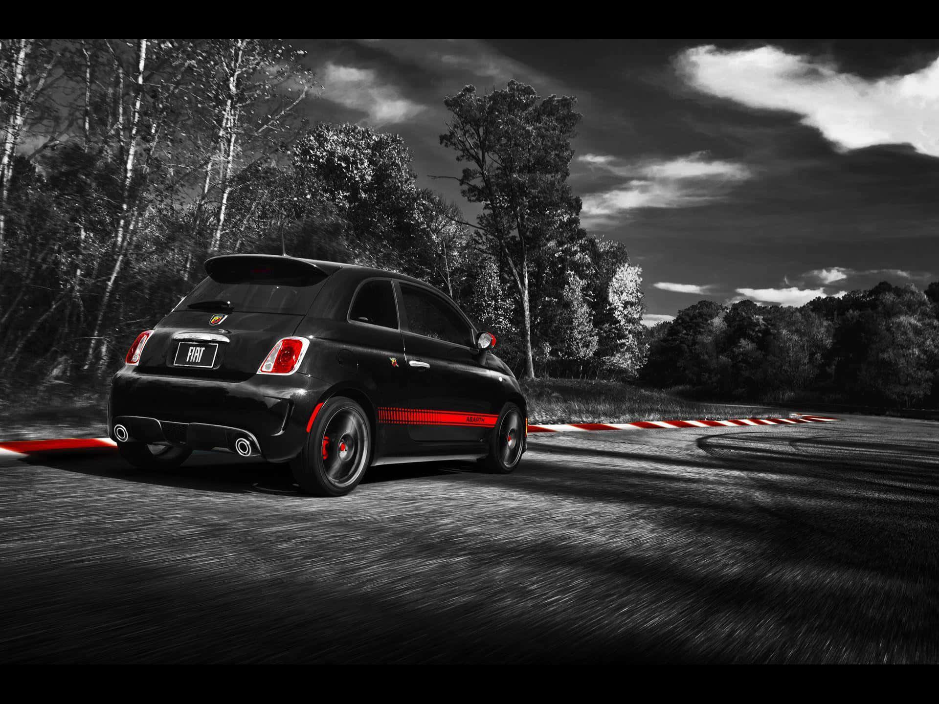 Abarth 桌布 壁紙 — 一輛帶有紅色點綴的黑色菲亞特500在陰沉單色天空下，沿著由紅白路緣圍繞的蜿蜒賽道疾馳。