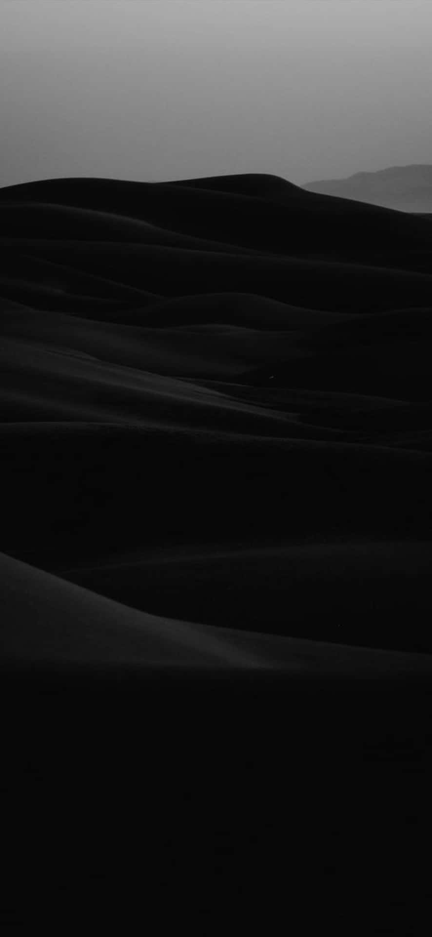  壁紙 — 單色沙丘在朦朧的天空下無盡延伸，柔和的陰影勾勒出它們起伏的形態。