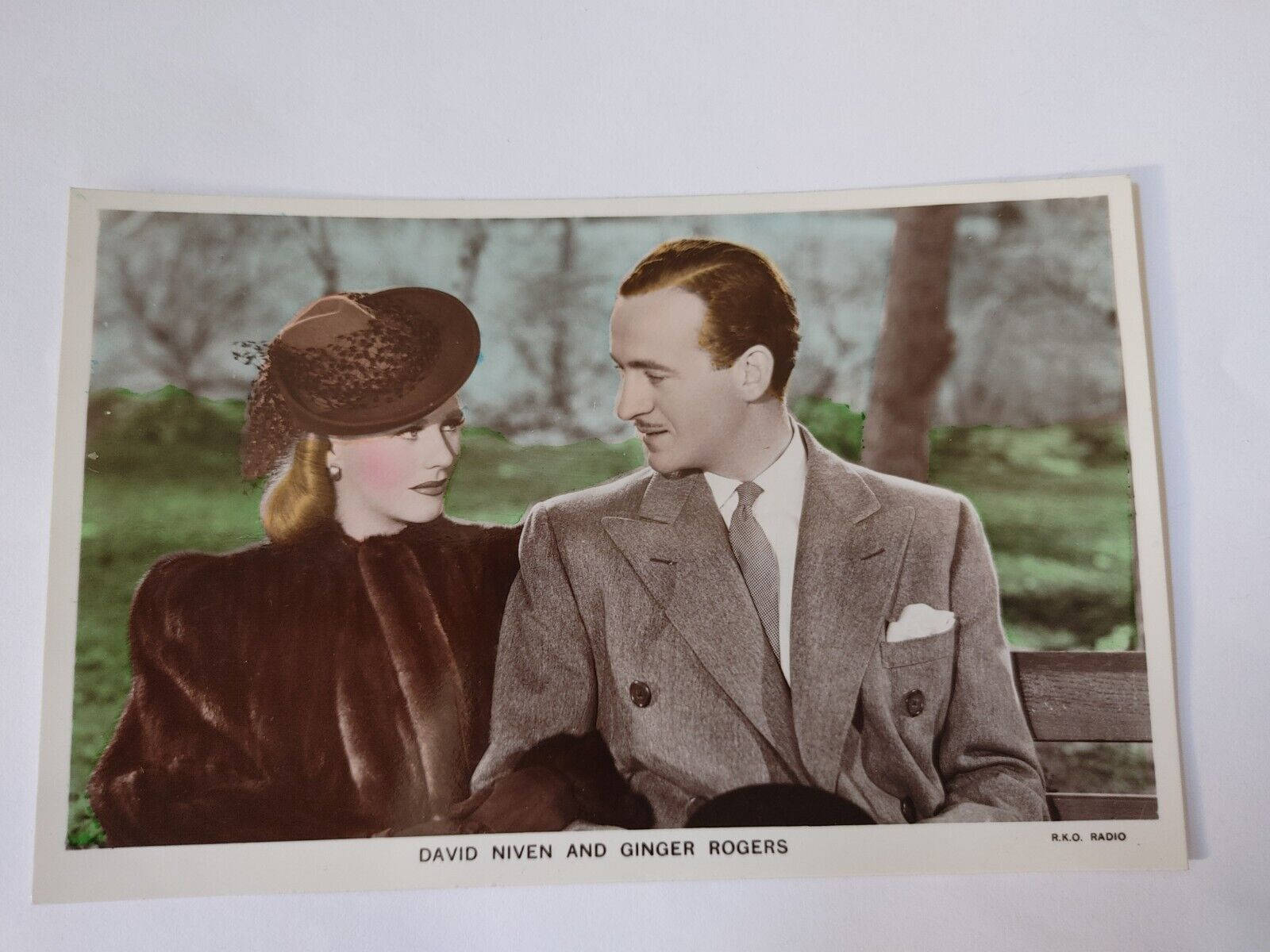 Celebrity 桌布 壁紙 — David Niven 和 Ginger Rogers 坐在公園長椅上溫柔時刻的復古彩色照片。