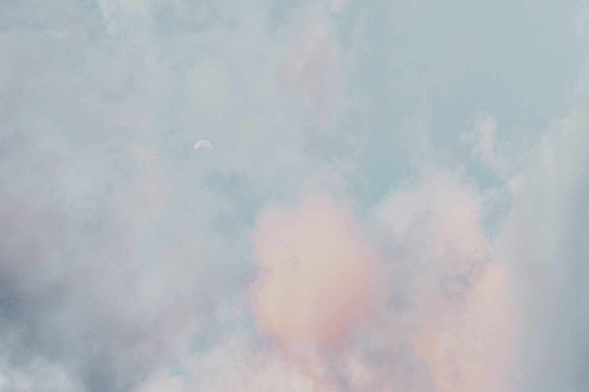 暮色中透過柔和粉紅和藍色雲層可見的眉月。 — Chromebook 壁紙