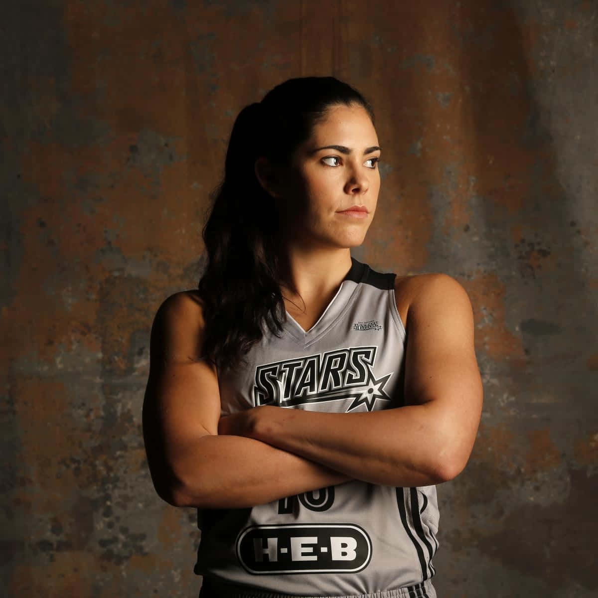 身穿Stars球衣的女籃球員，雙臂交叉靠著鏽牆。 — NBA 壁紙