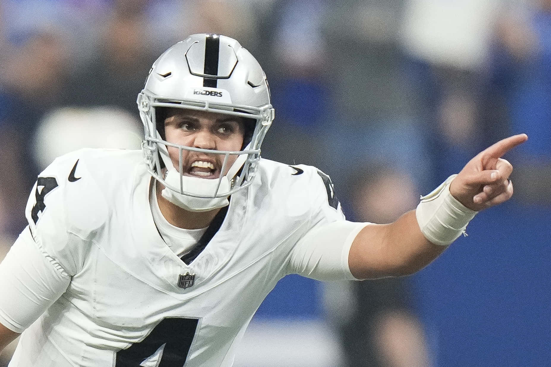  壁紙 — 一位堅定的NFL四分衛穿著白色Raiders球衣，在體育場燈光下比賽中激烈地喊叫和指點。