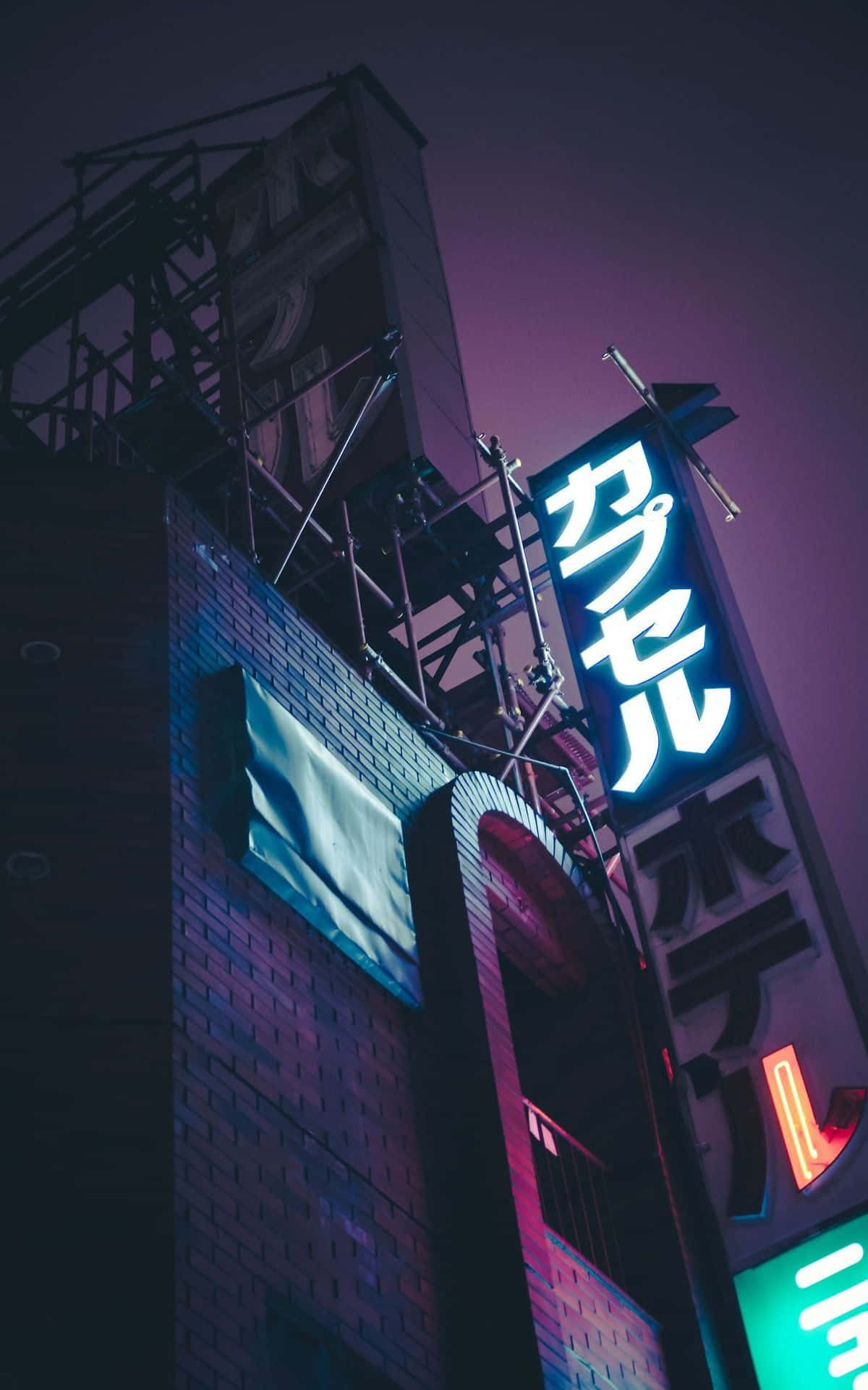  壁紙 — 低角度拍攝霓虹燈照亮的日本酒店招牌，在暮色天空下發光。
