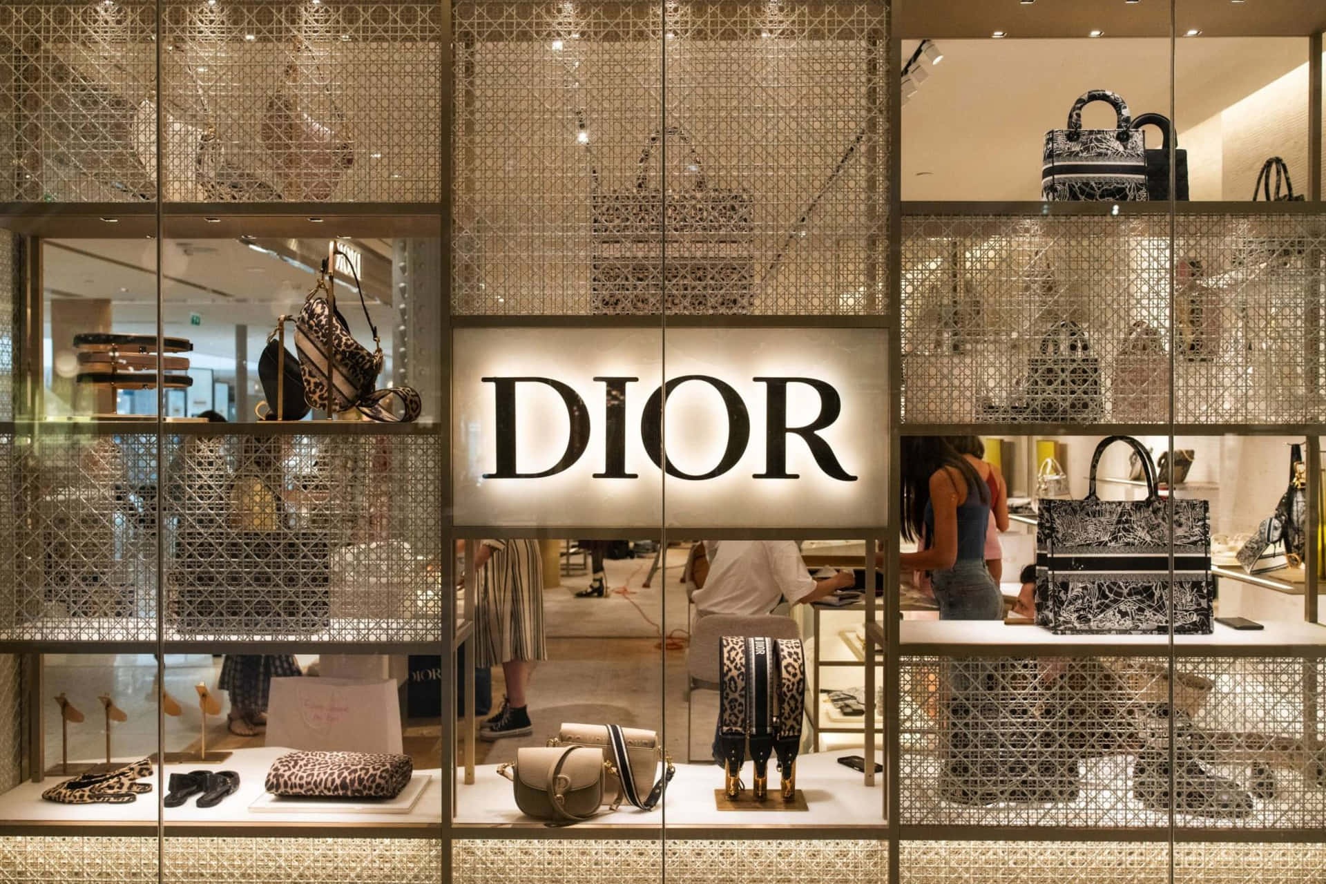 Dior 動態 桌布 壁紙 — Dior 奢華精品店櫥窗展示，幾何網格面板後方展示圖案手袋和鞋子，配以發光標誌。