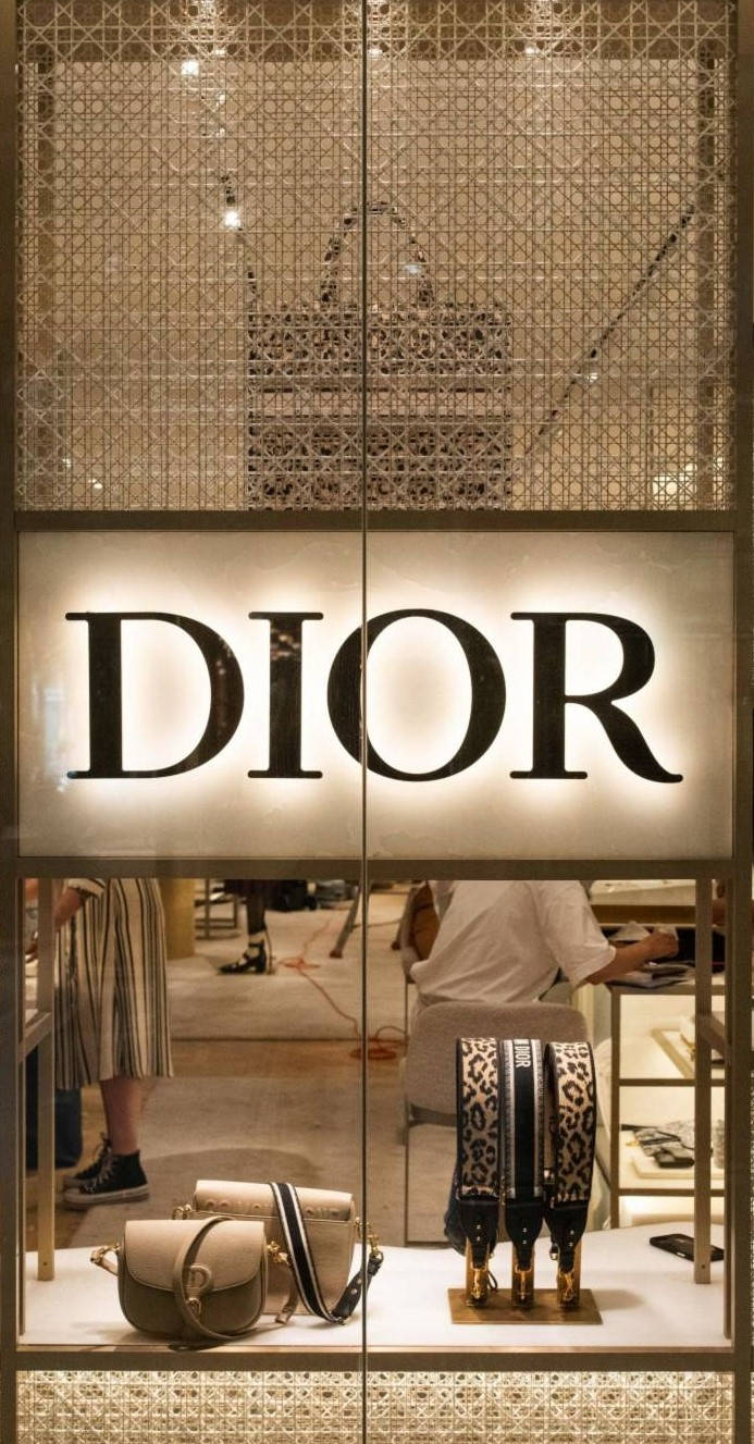 桌布 壁紙 — Dior 精品店櫥窗展示，在溫暖燈光下展示奢華手提包和豹紋肩帶。