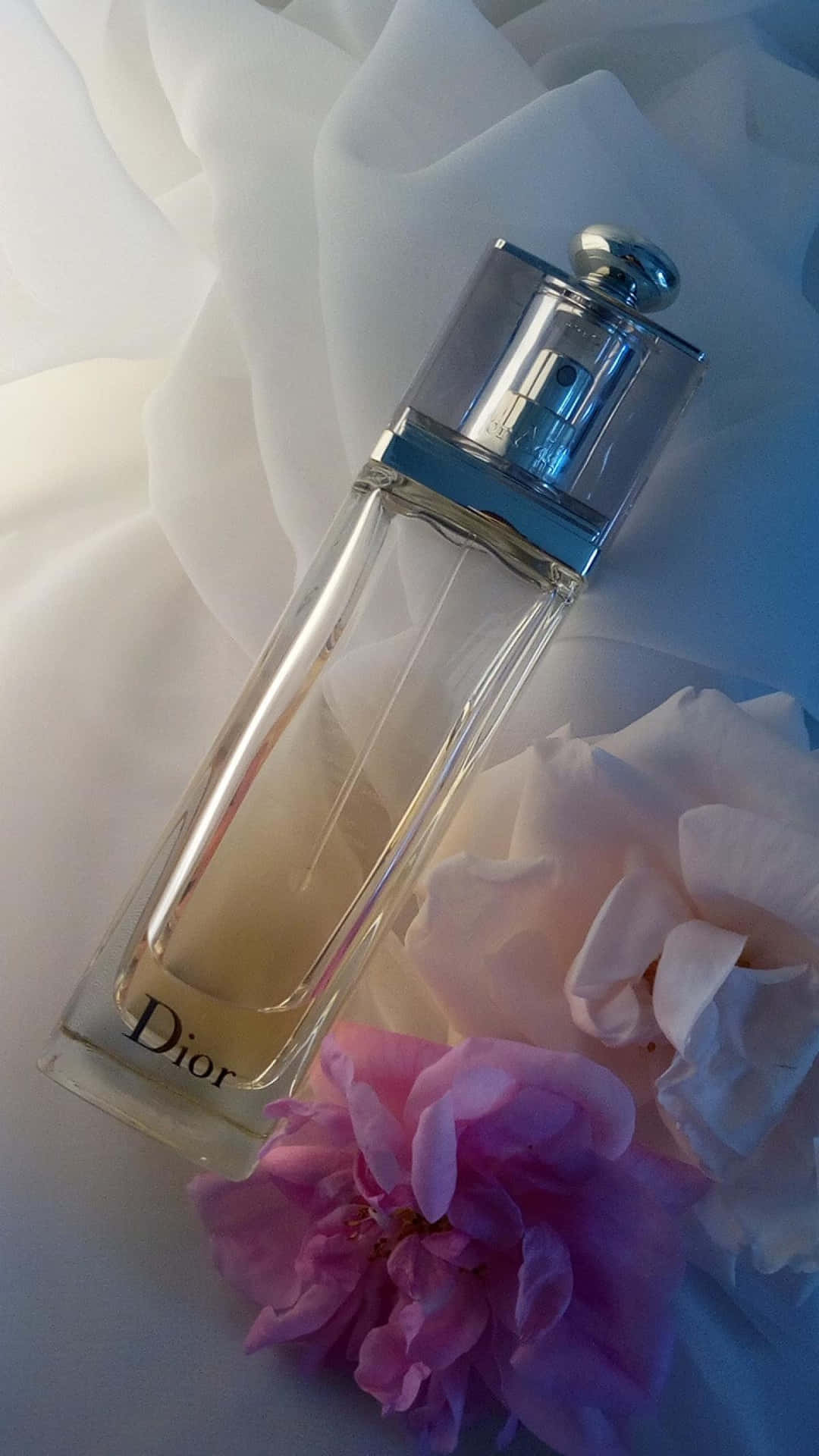 Dior 動態 桌布 壁紙 — Dior 香水瓶優雅地放在柔軟的白色布料上，旁邊有精緻的粉紅色和白色花朵。