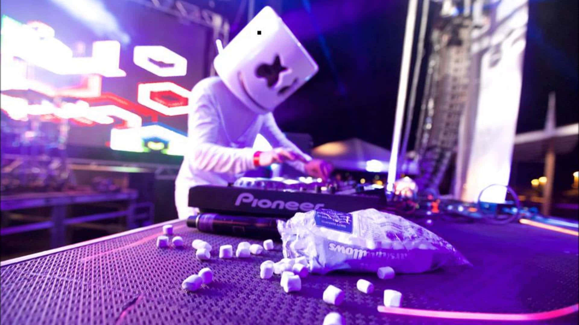 Marshmello 動態圖 桌布 壁紙 — DJ Marshmello 在夜晚的霓虹燈下表演，桌上散落著棉花糖。