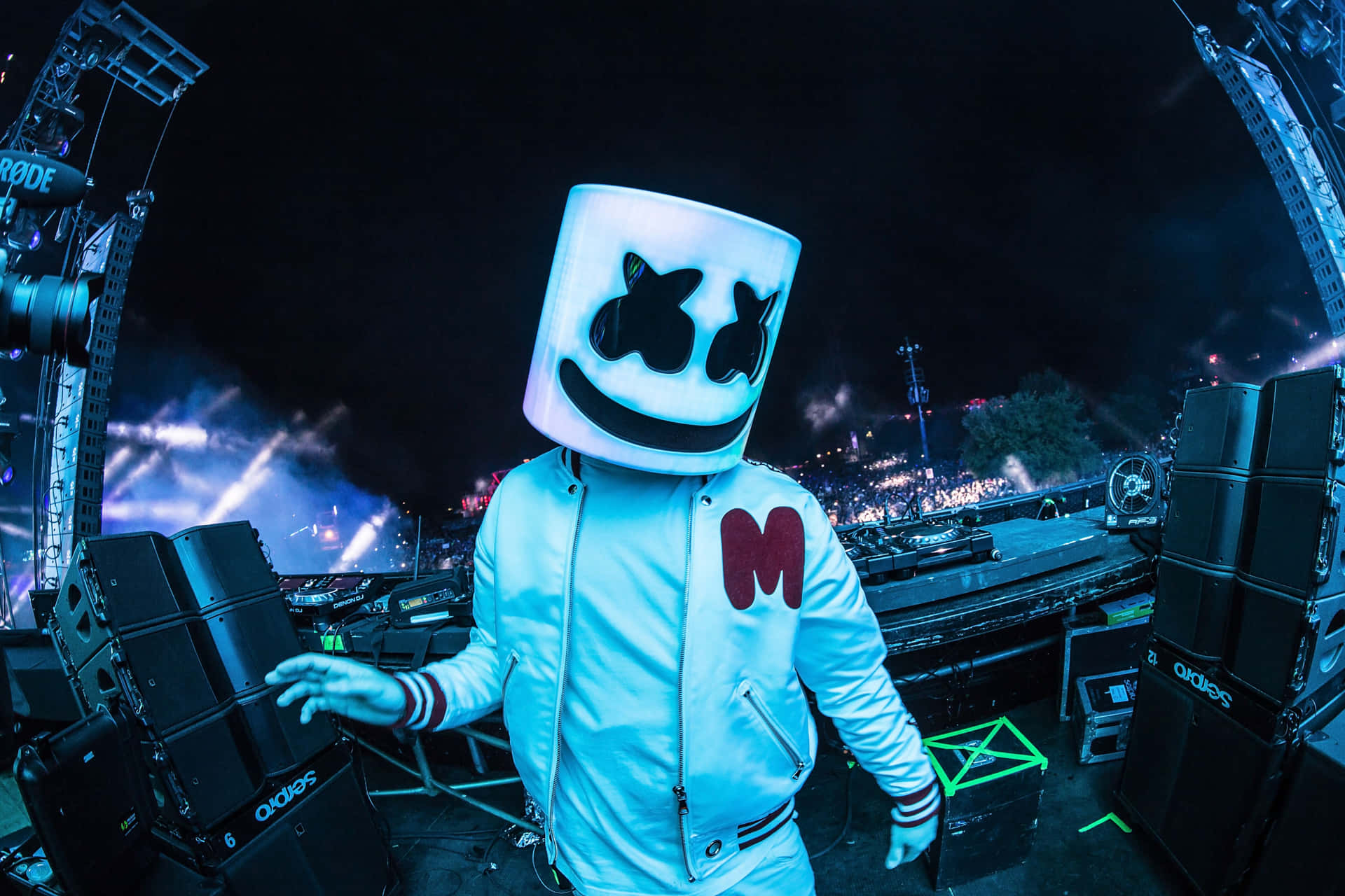 DJ Marshmello 戴著白色頭盔和外套，在夜晚的燈光舞台上。 — DJ GIF 壁紙