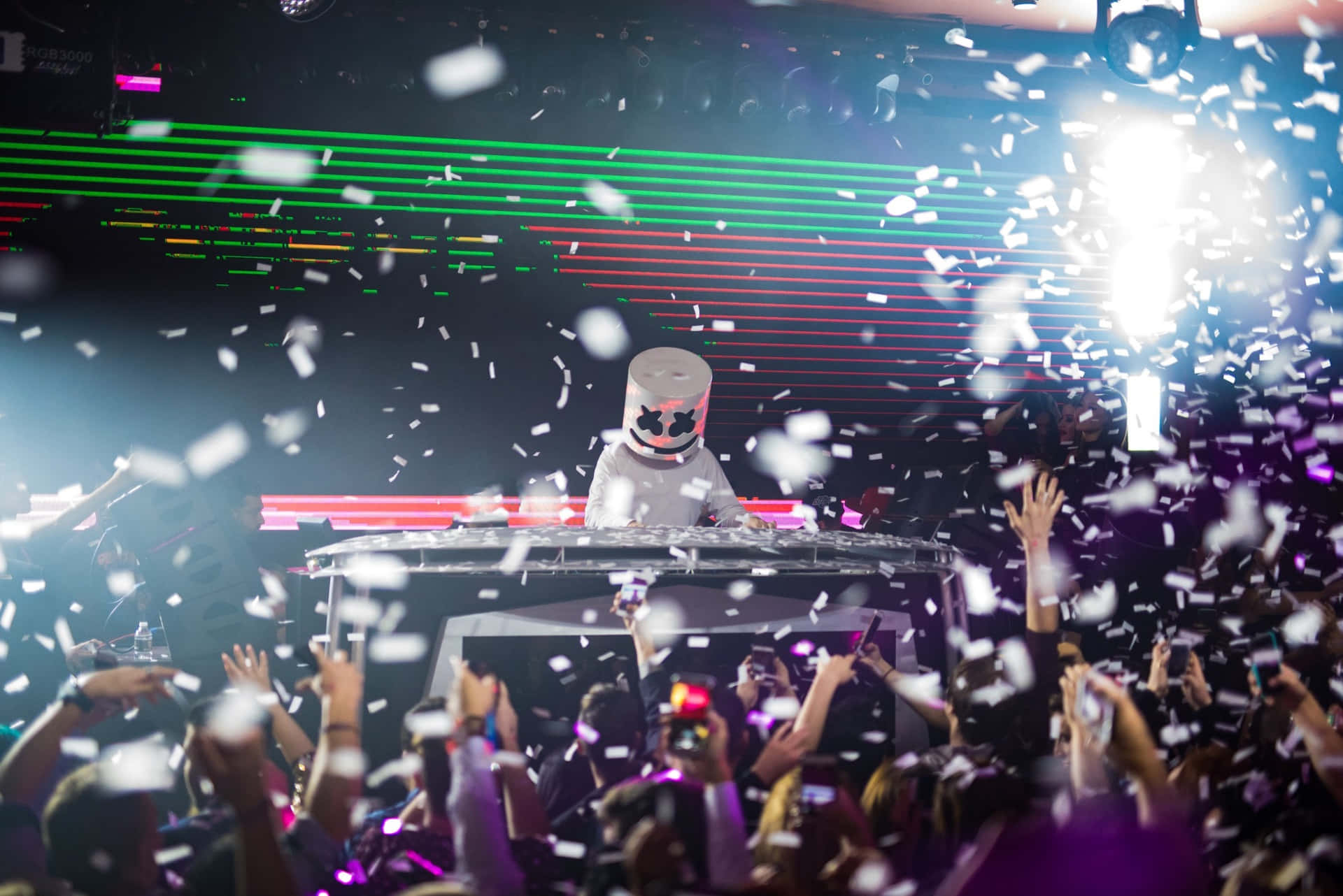 Marshmello 動態圖 桌布 壁紙 — DJ Marshmello 在演唱會上表演，五彩紙屑在充滿活力的雷射燈光下灑向狂歡的人群。