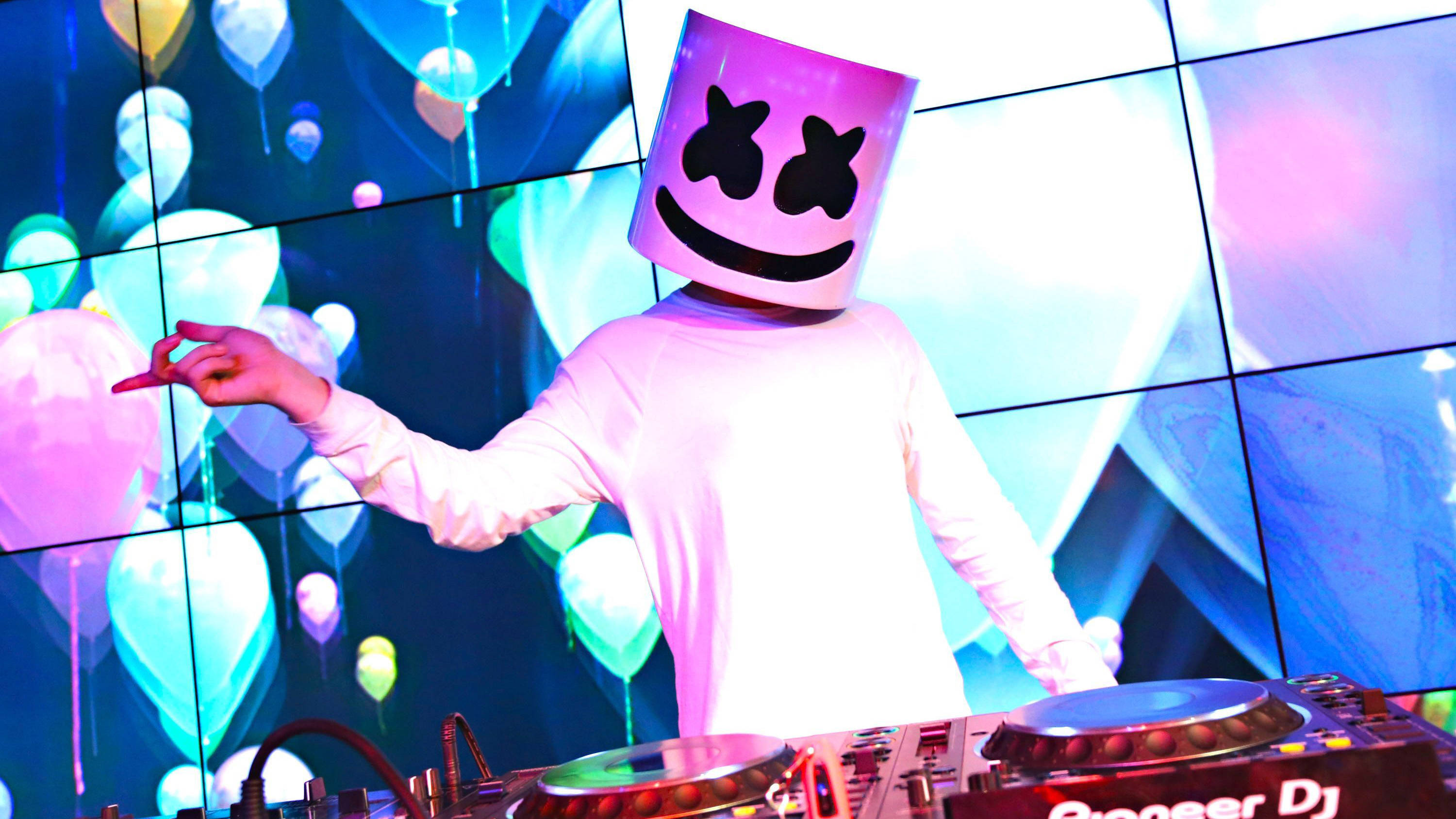 Marshmello 4K 桌布 壁紙 — DJ Marshmello 戴上標誌性頭盔，在充滿活力的夜總會表演，身後有發光的氣球視覺效果。