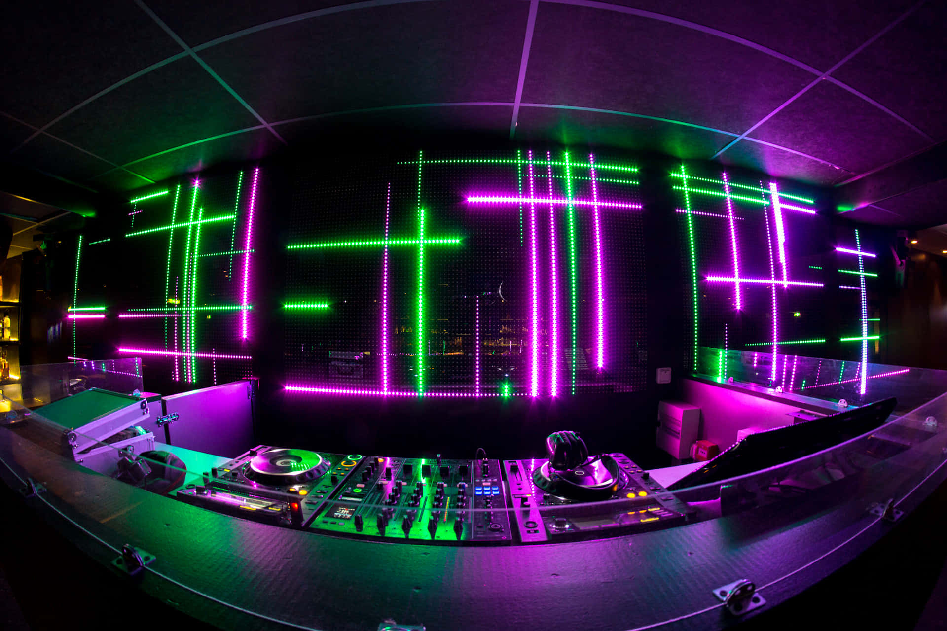 DJ 台配有霓虹綠色和紫色燈光，牆上帶有發光的網格圖案。 — DJ GIF 壁紙