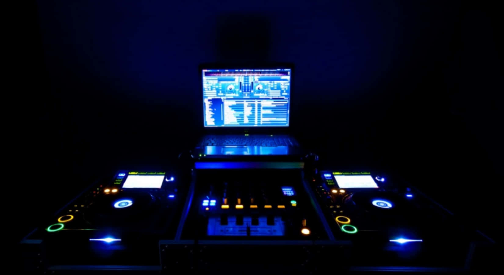 音樂 桌布 壁紙 — DJ 設備在黑暗的房間中發出藍色和橙色的光芒，筆記型電腦顯示音樂軟體。